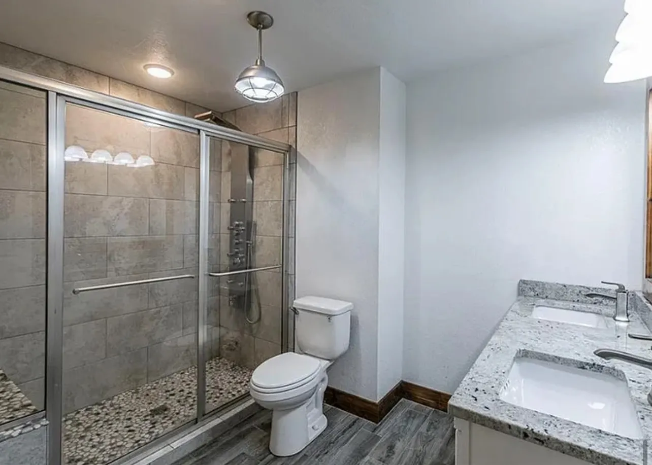 Full bath featuring a shower stall, double vanity, and dark wood finished floors