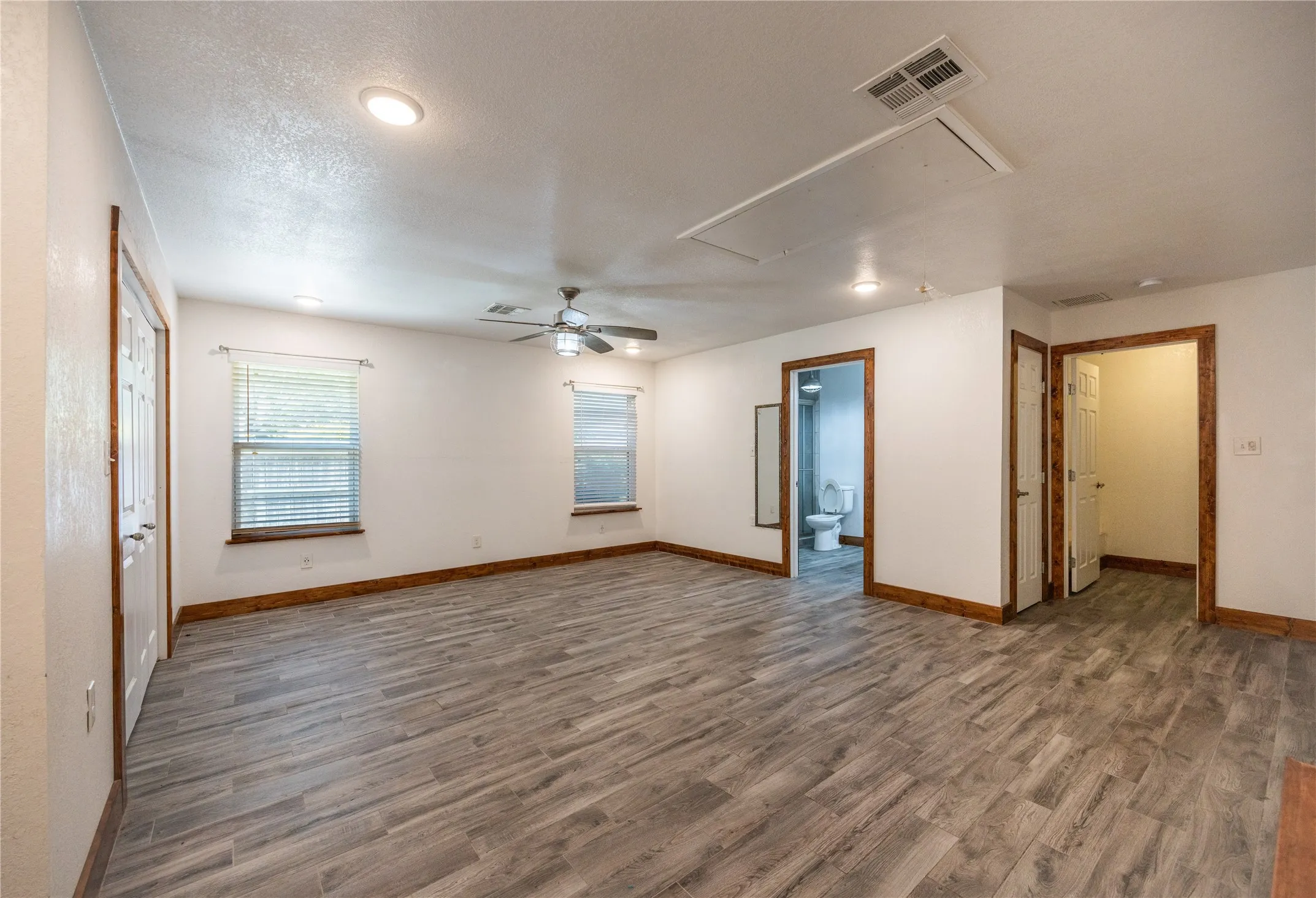 Spare room with wood finished floors, a ceiling fan, attic access, and a textured ceiling