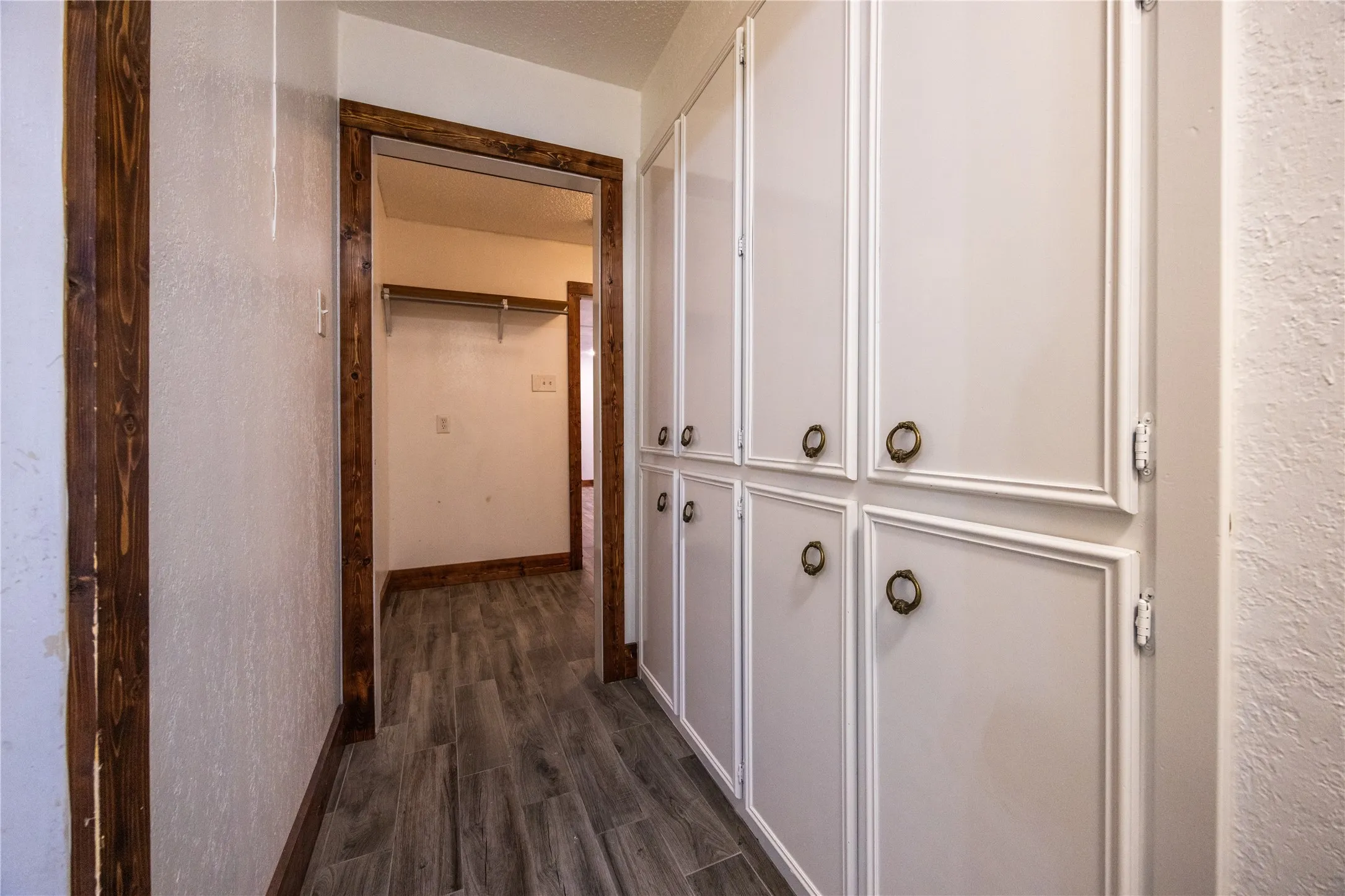 Hallway featuring dark wood finished floors and a textured wall