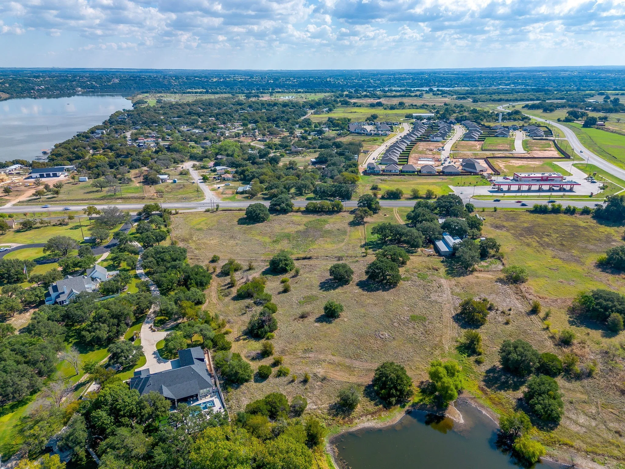 Aerial view of property and surrounding area with a nearby body of water and a tree filled landscape