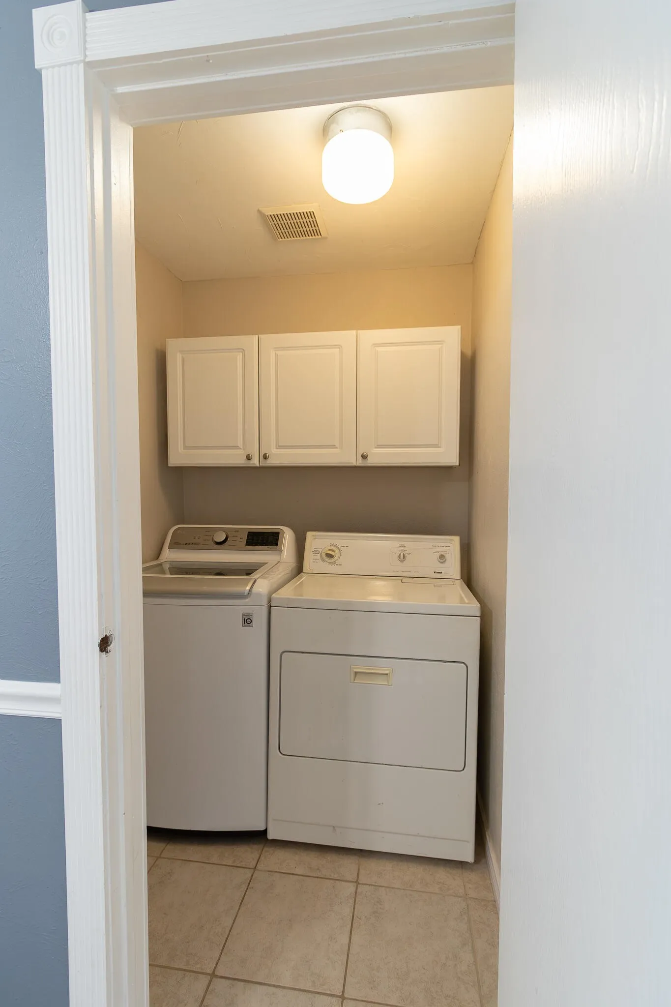 Laundry room featuring light tile patterned floors, cabinet space, and washer and clothes dryer
