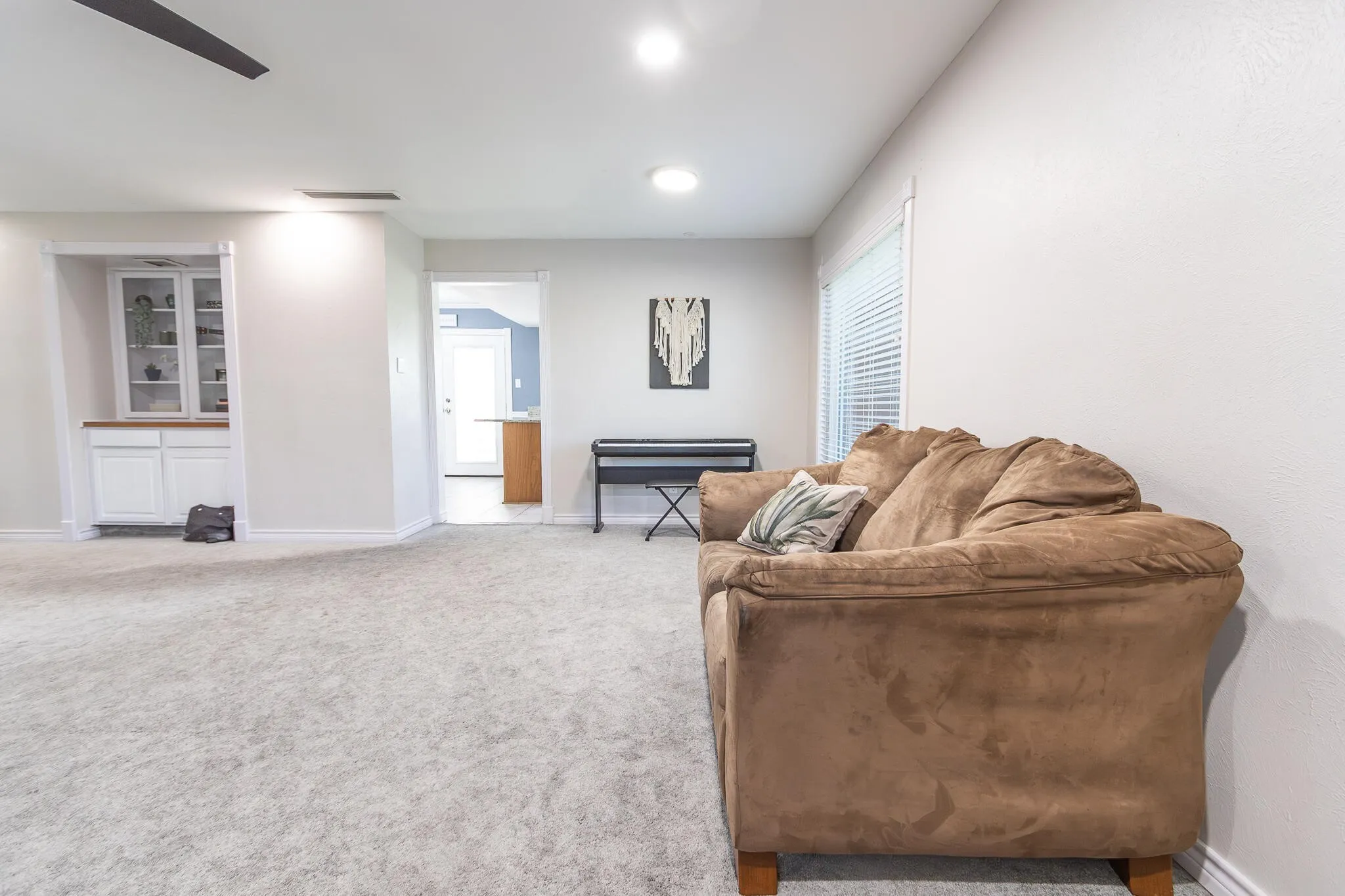 Living area with light carpet and recessed lighting