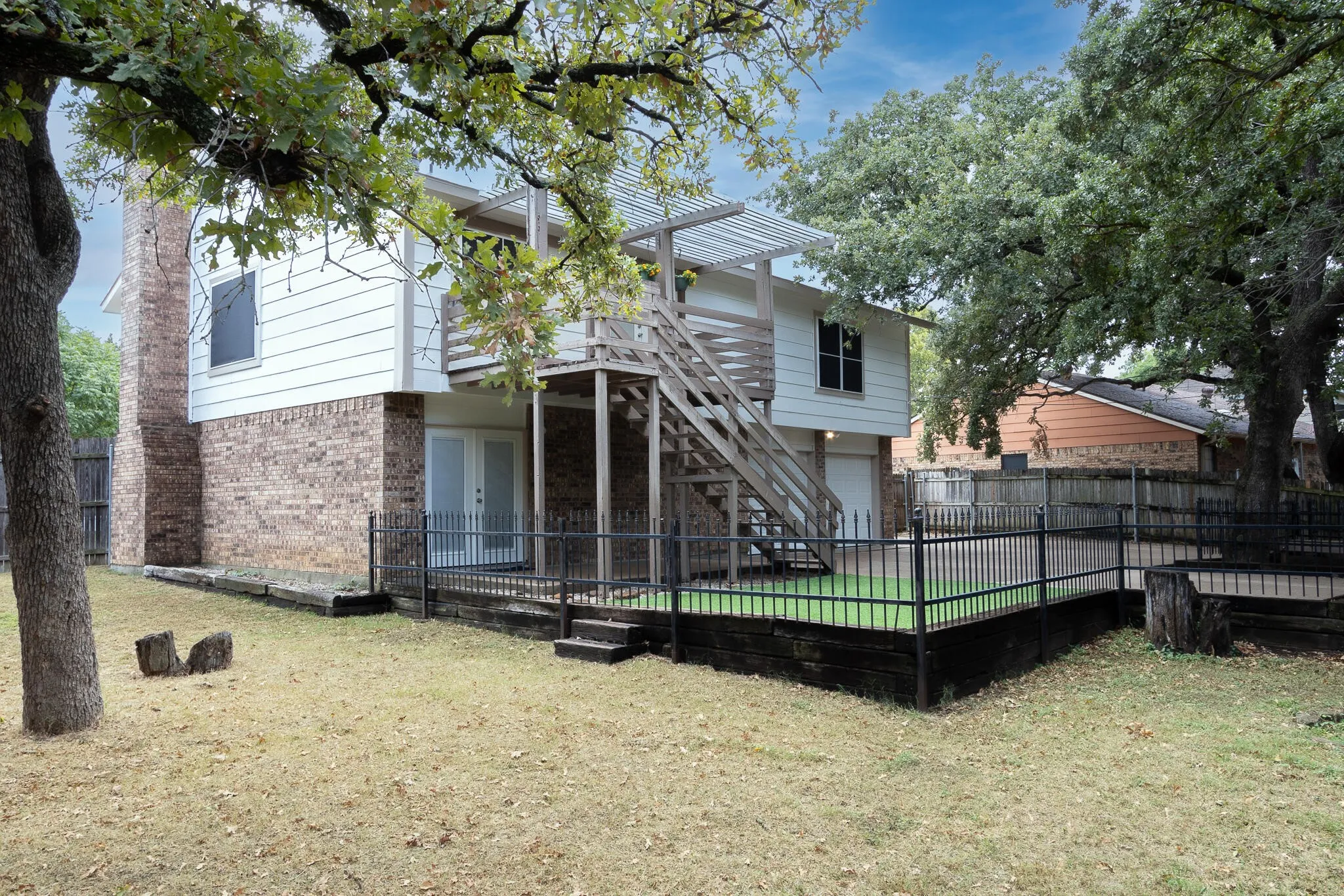 Rear view of property with stairway, a fenced backyard, brick siding, and a patio area