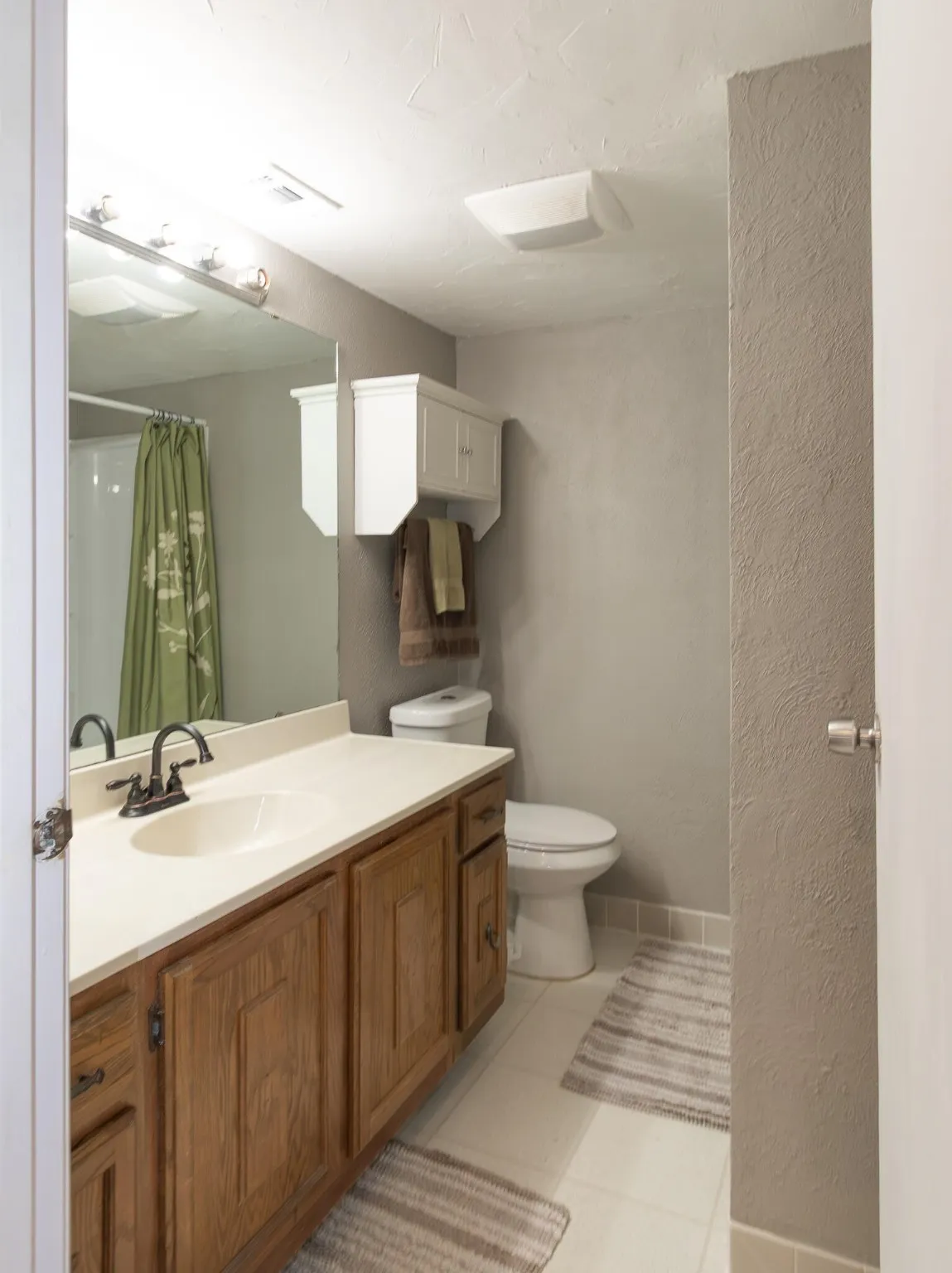 Full bathroom featuring a textured wall, vanity, light tile patterned flooring, and a shower with shower curtain