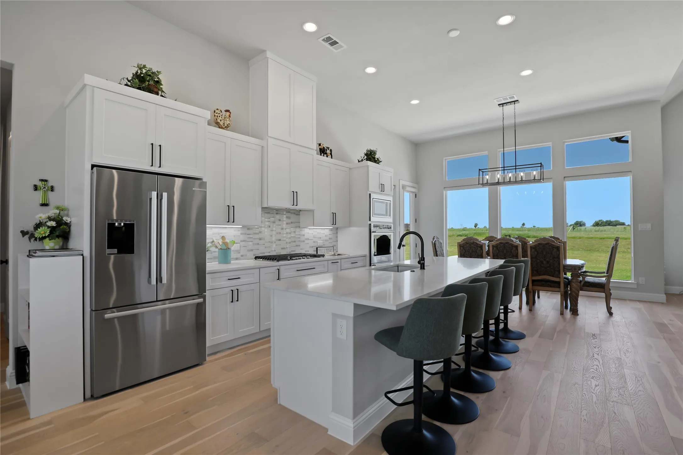 Kitchen with stainless steel appliances, white cabinetry, light wood finished floors, tasteful backsplash, and recessed lighting