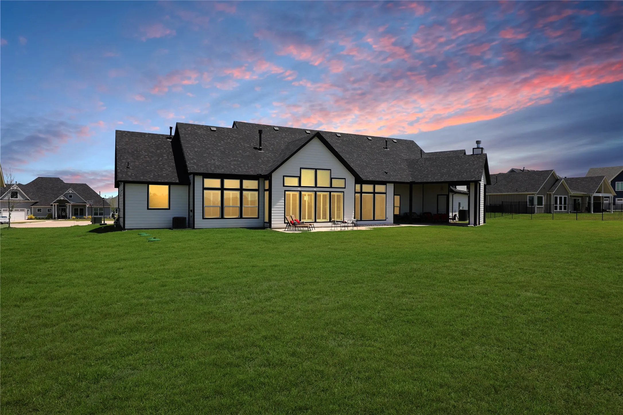Back of house featuring a patio, a lawn, and roof with shingles