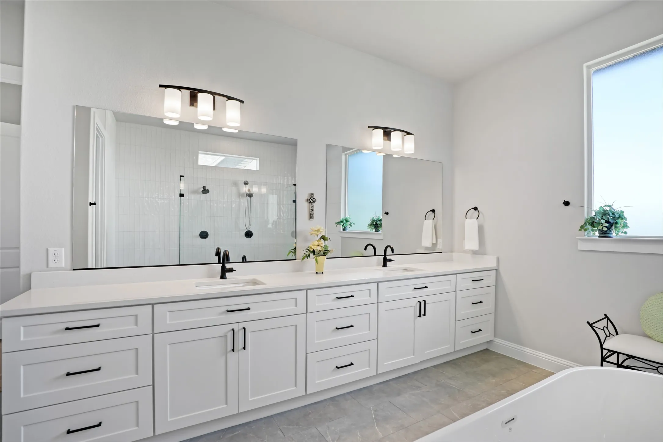 Bathroom with double vanity, plenty of natural light, and a freestanding tub