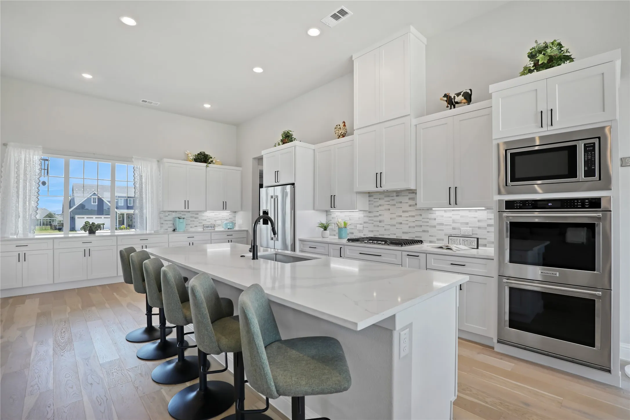Kitchen with white cabinetry, appliances with stainless steel finishes, a breakfast bar area, recessed lighting, and a center island with sink