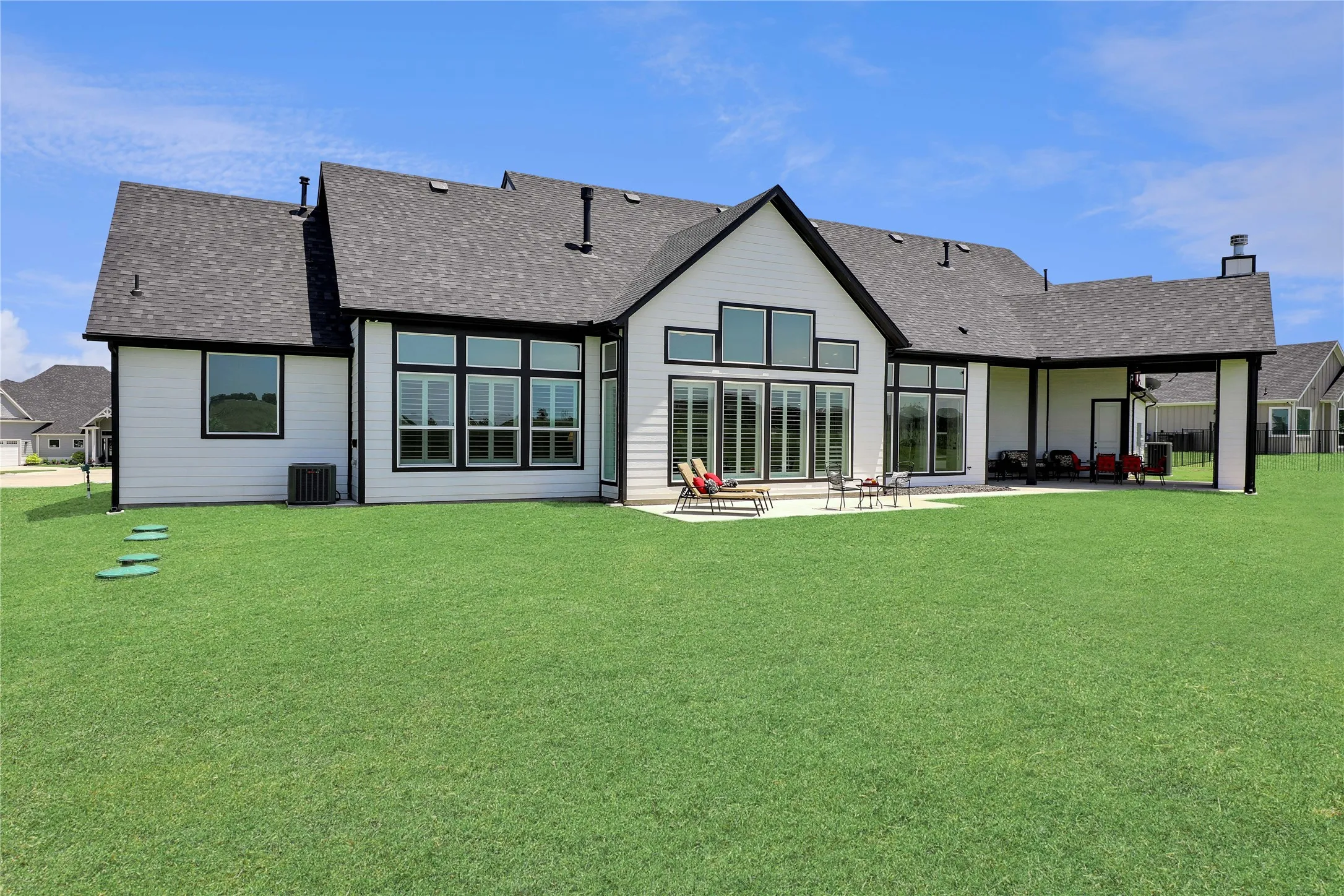 Rear view of house featuring roof with shingles, a patio area, and a lawn