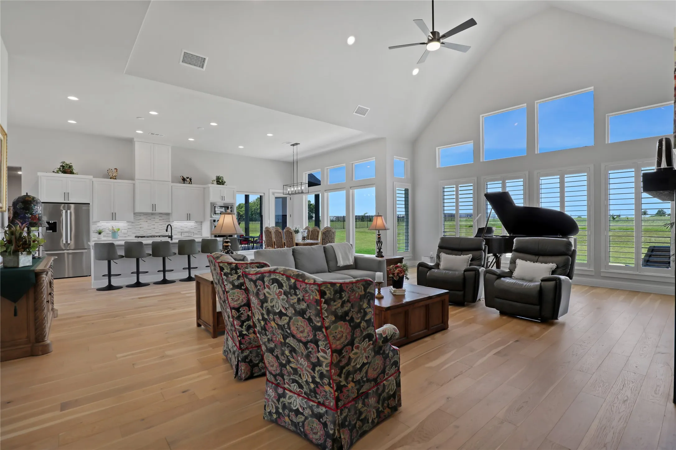 Living area with high vaulted ceiling, light wood finished floors, recessed lighting, and a ceiling fan