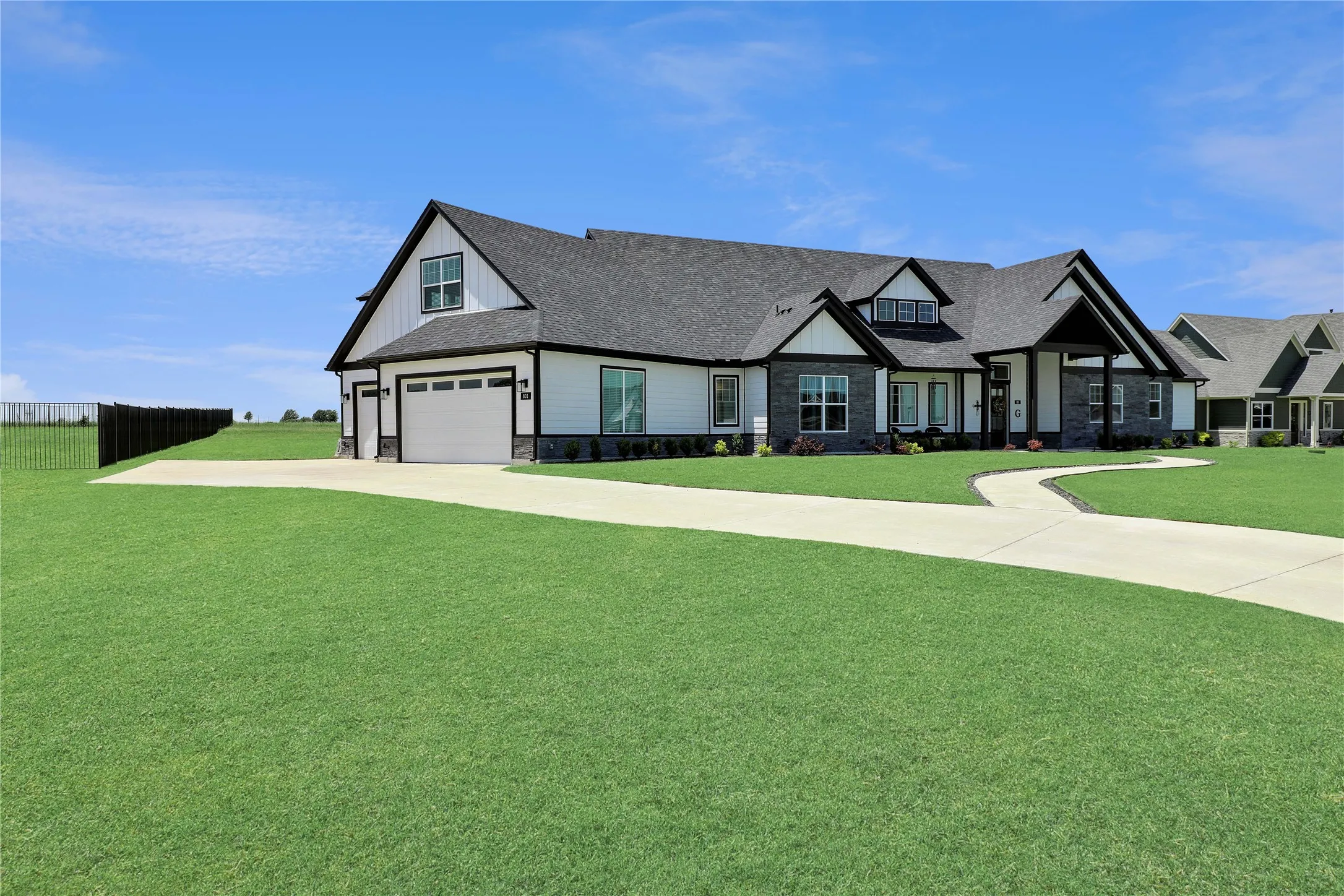 Modern farmhouse style home with stone siding, concrete driveway, and roof with shingles