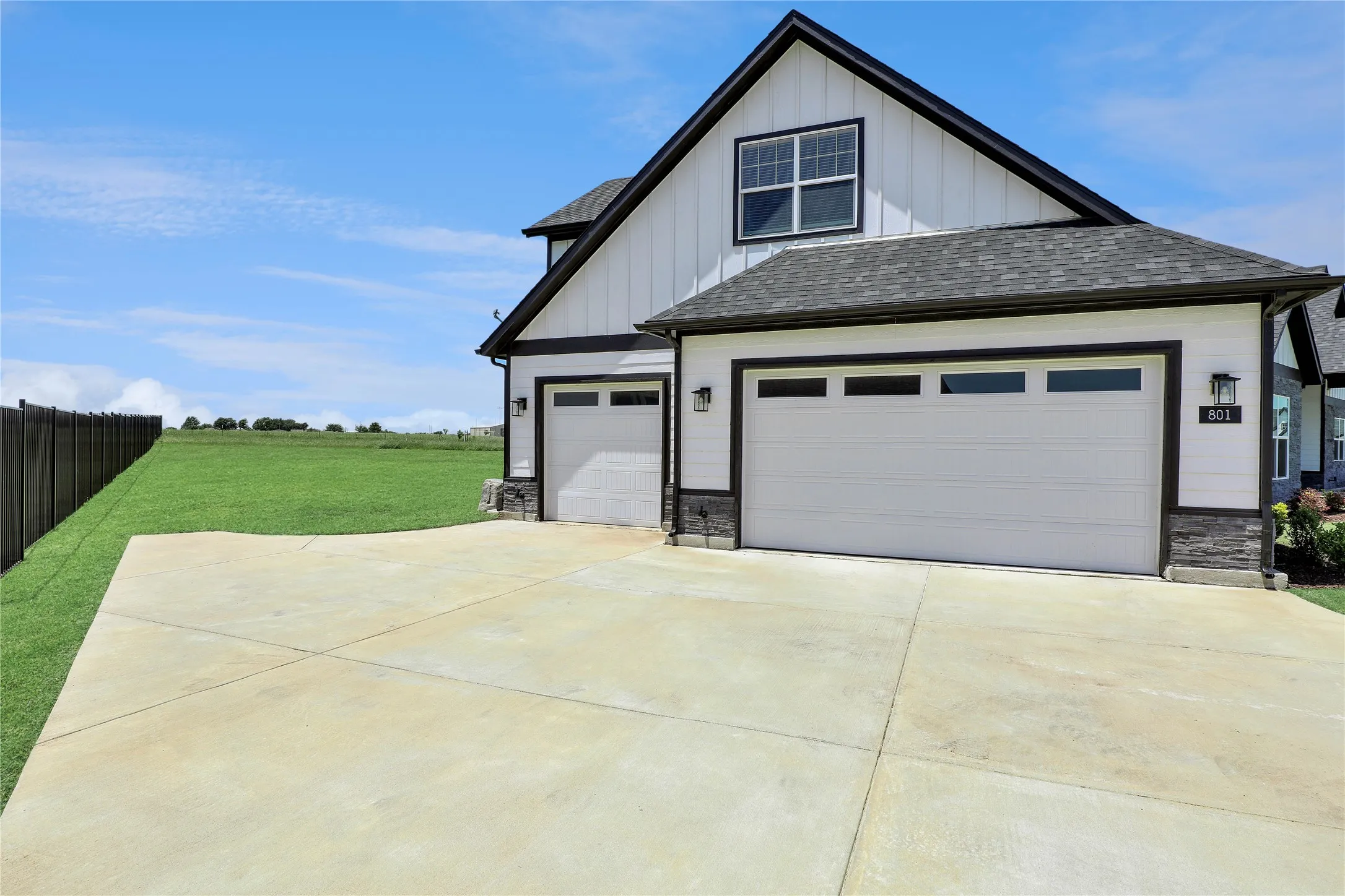 View of front of property with board and batten siding, stone siding, driveway, a shingled roof, and an attached garage