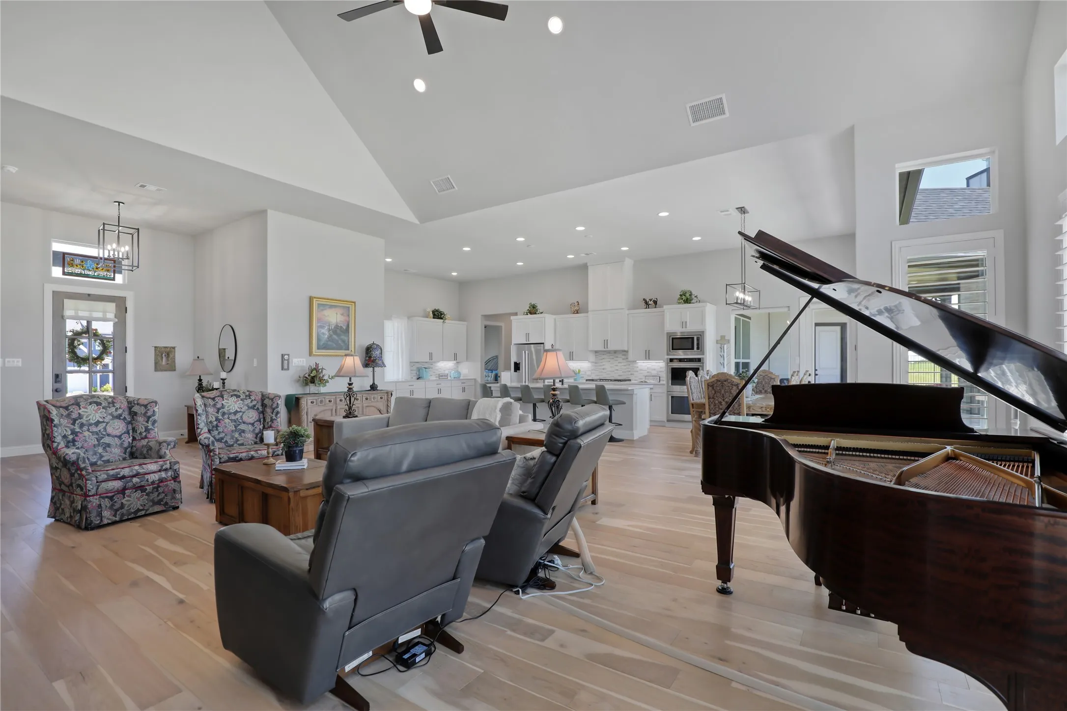 Living room with high vaulted ceiling, light wood-style flooring, recessed lighting, and a chandelier