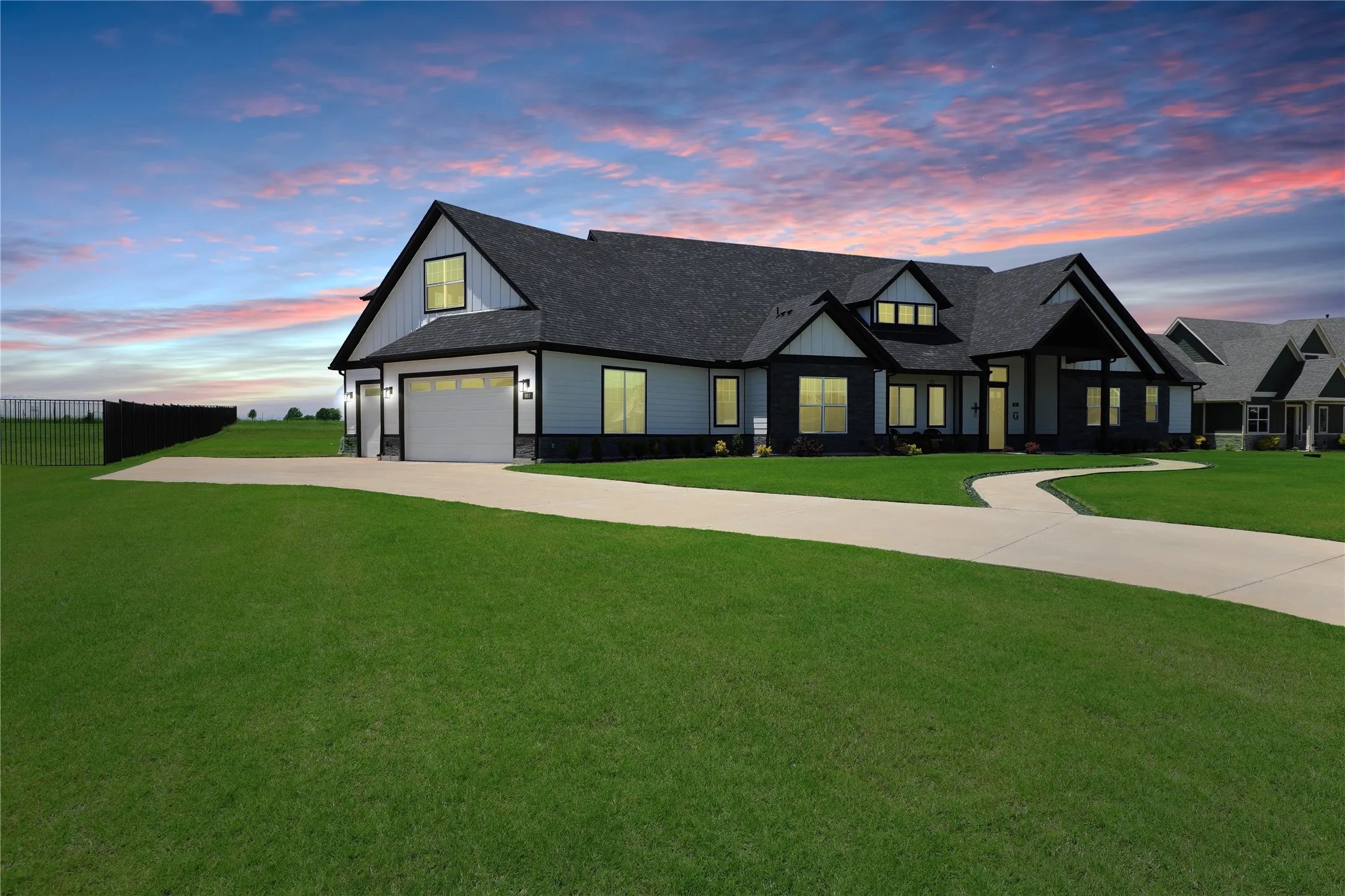 Modern farmhouse featuring concrete driveway, a garage, a shingled roof, board and batten siding, and stone siding