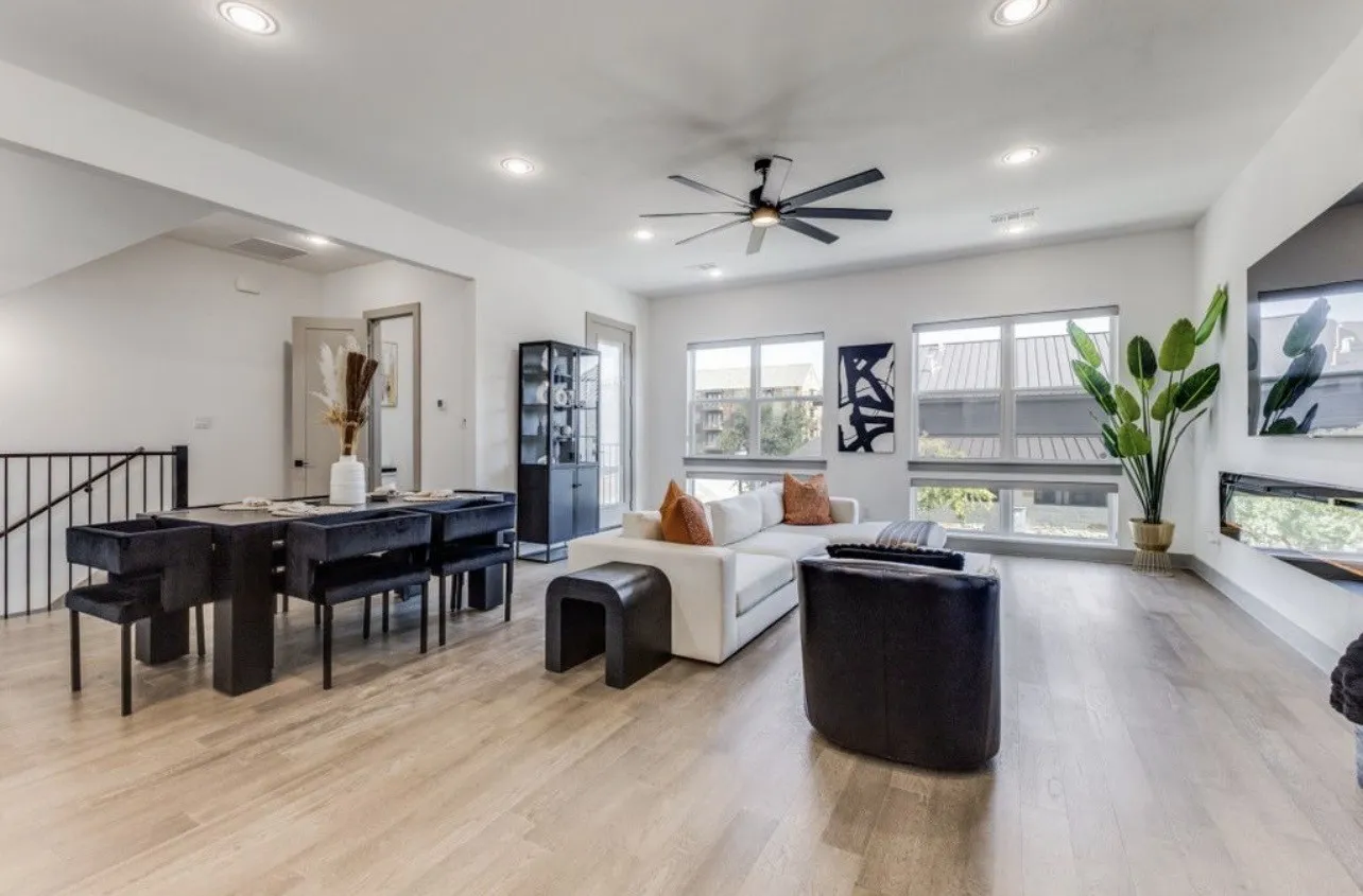 Living room with family-sized ceiling fan, light wood floors, open to the kitchen