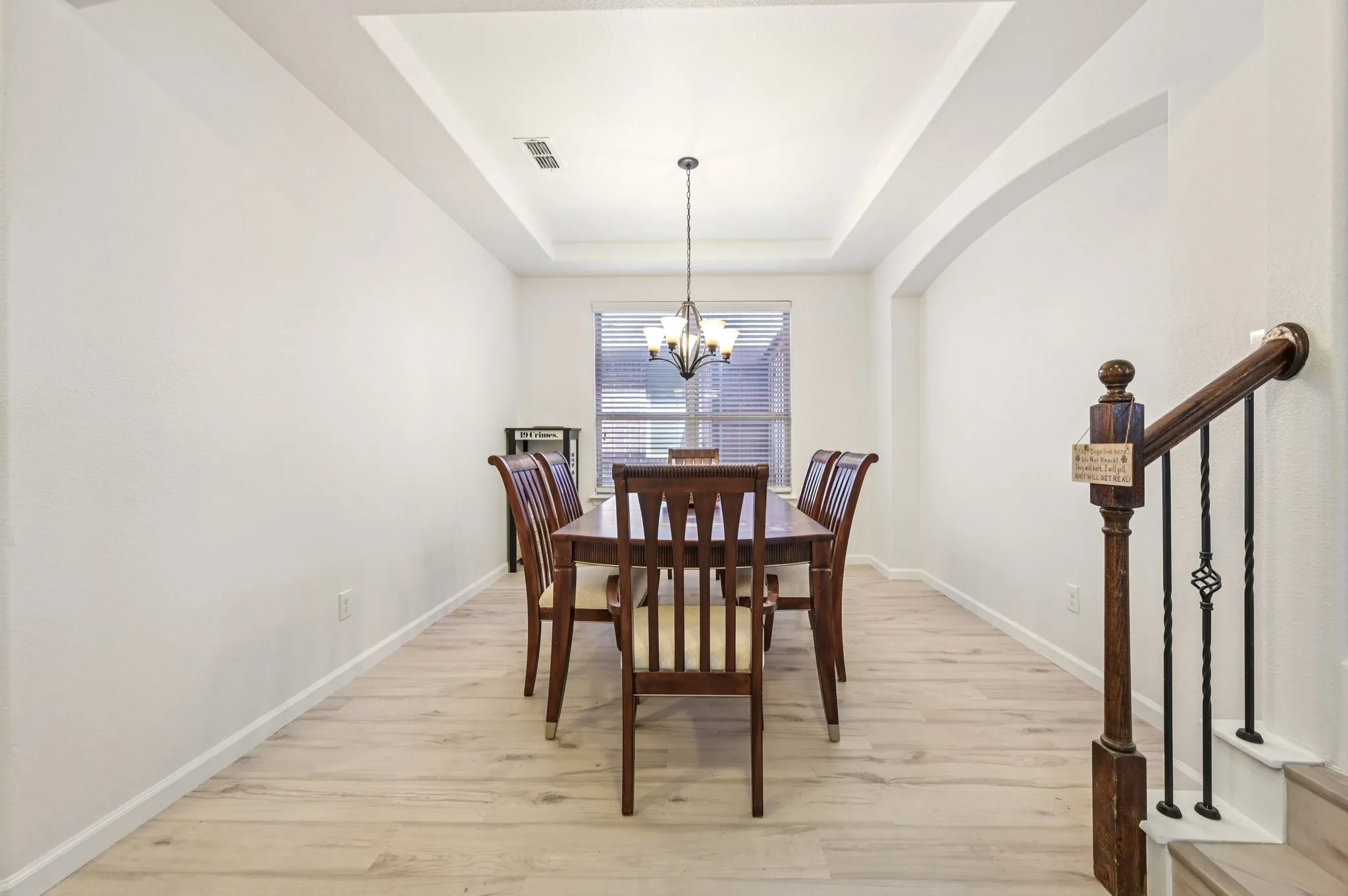 Dining space featuring light wood-style floors, a chandelier, a tray ceiling, and stairway
