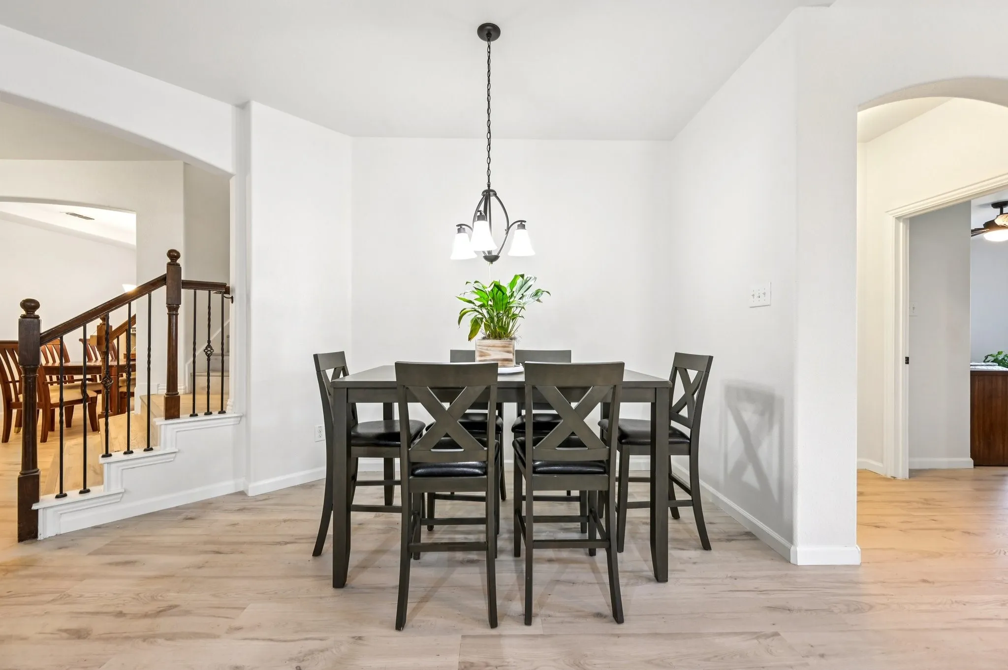 Dining area with arched walkways, light wood finished floors, a chandelier, and stairs