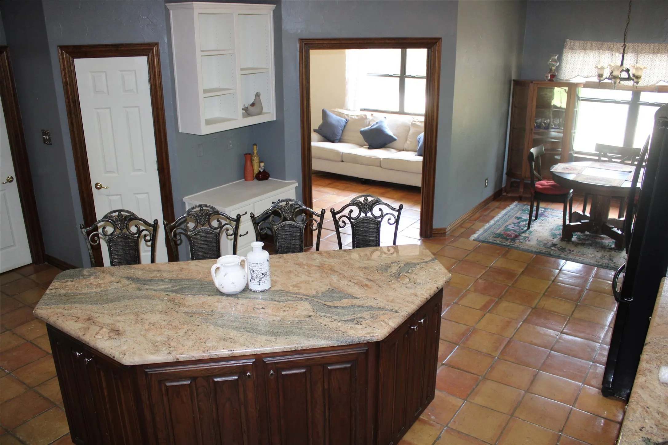 Kitchen featuring light stone countertops, light tile patterned flooring, an inviting chandelier, and dark brown cabinets