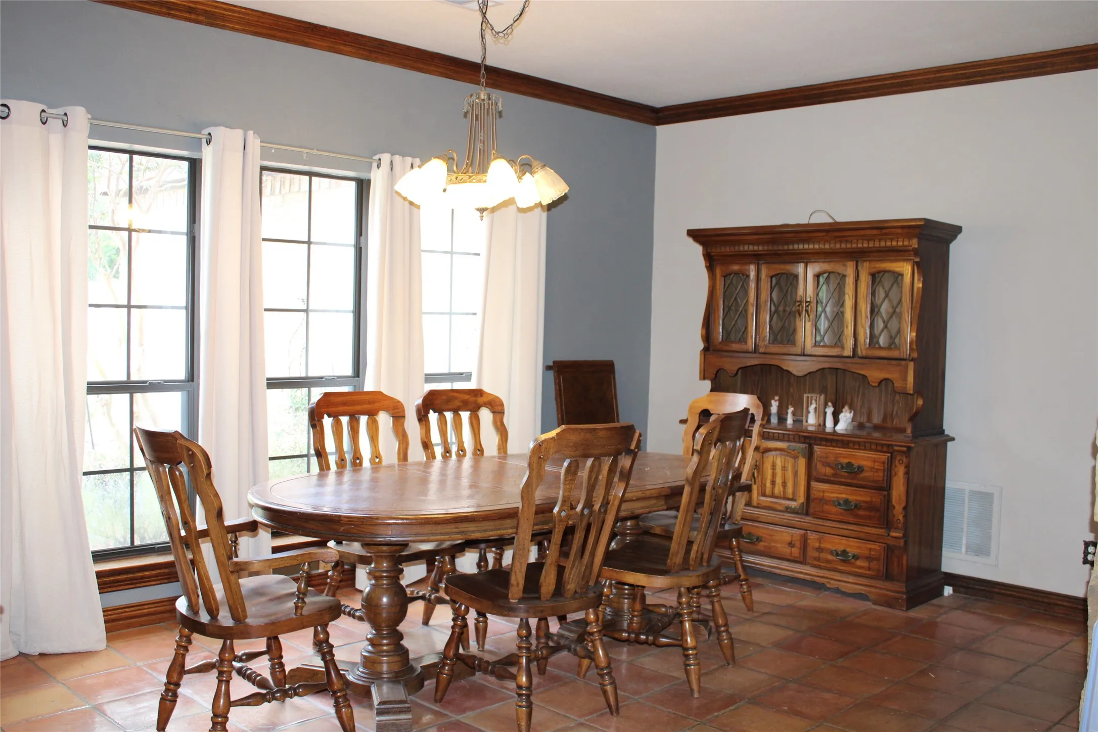 Dining room with tile patterned floors, ornamental molding, a chandelier, and a wealth of natural light