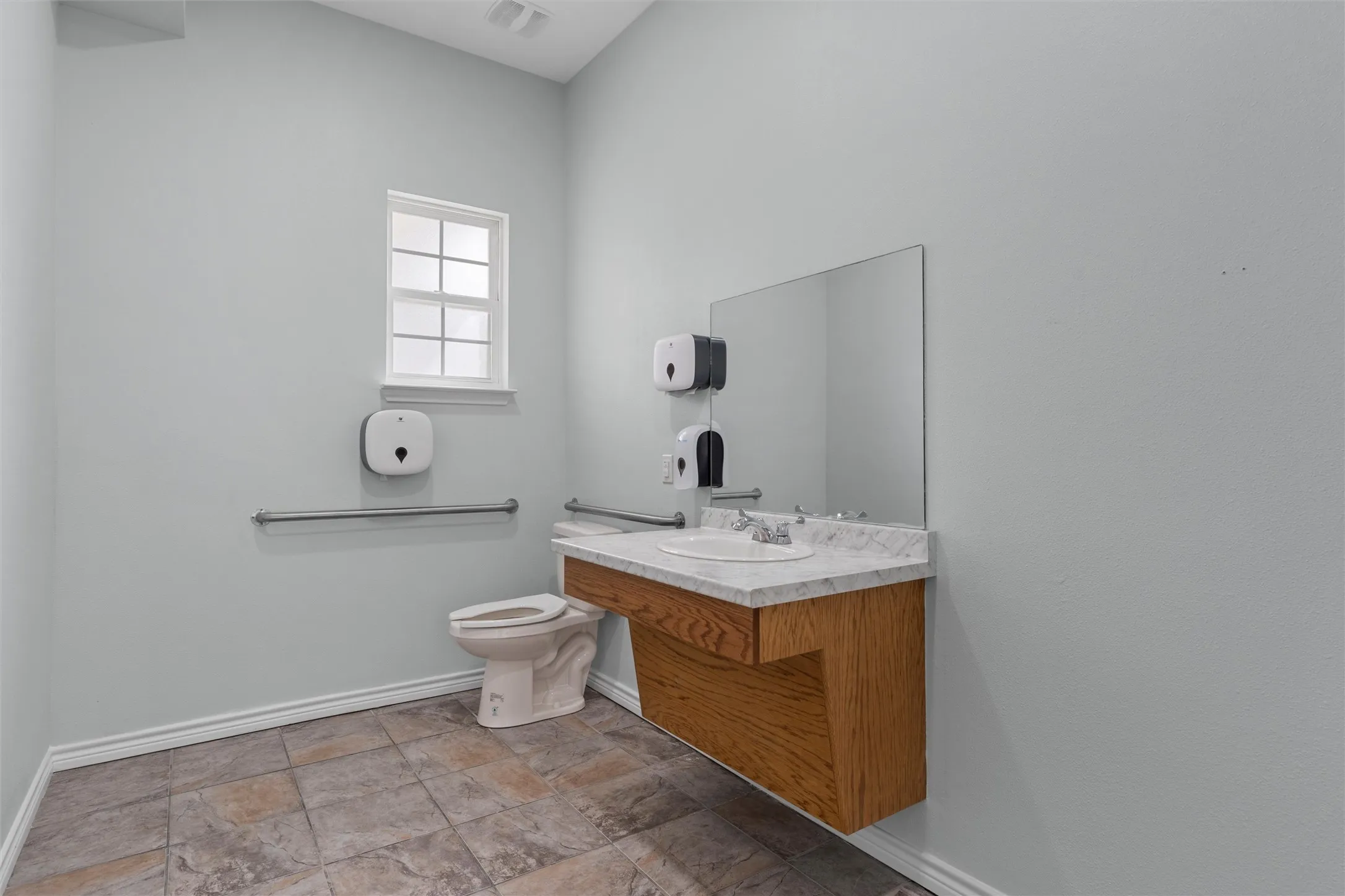 Bathroom with vanity and light stone finish floors