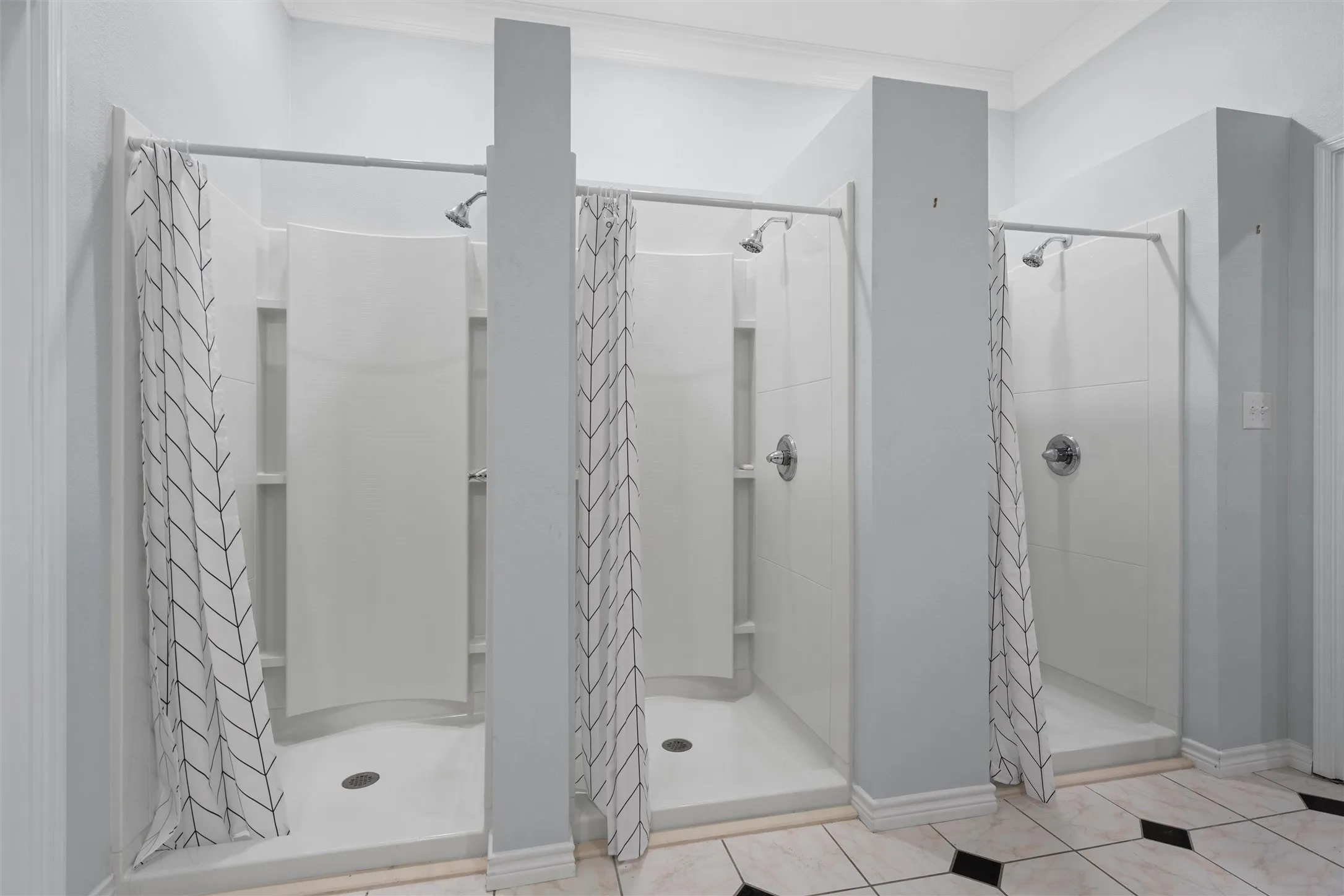 Full bathroom with a shower stall, light tile patterned floors, and crown molding
