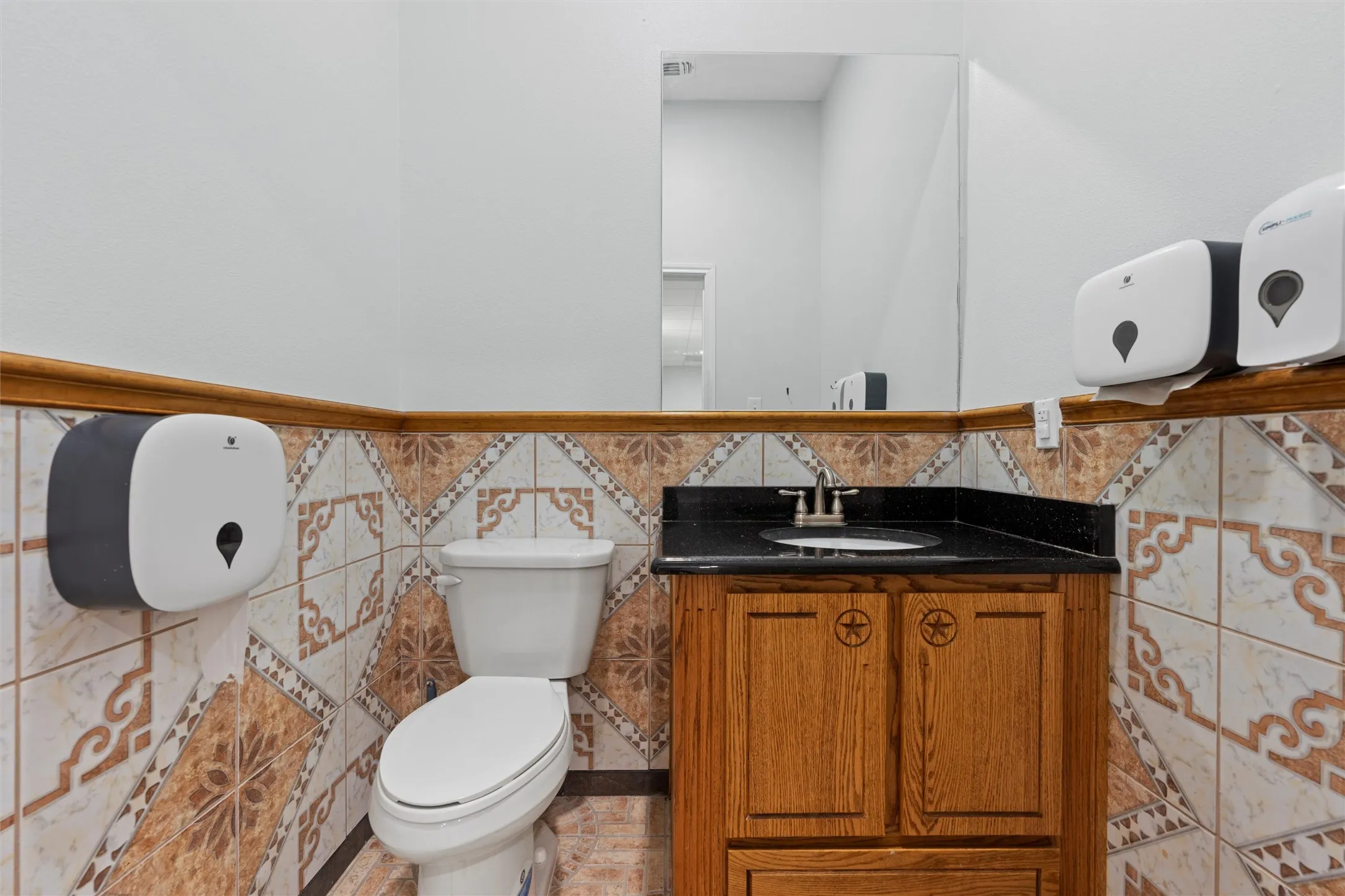Bathroom featuring tile walls, wainscoting, and vanity