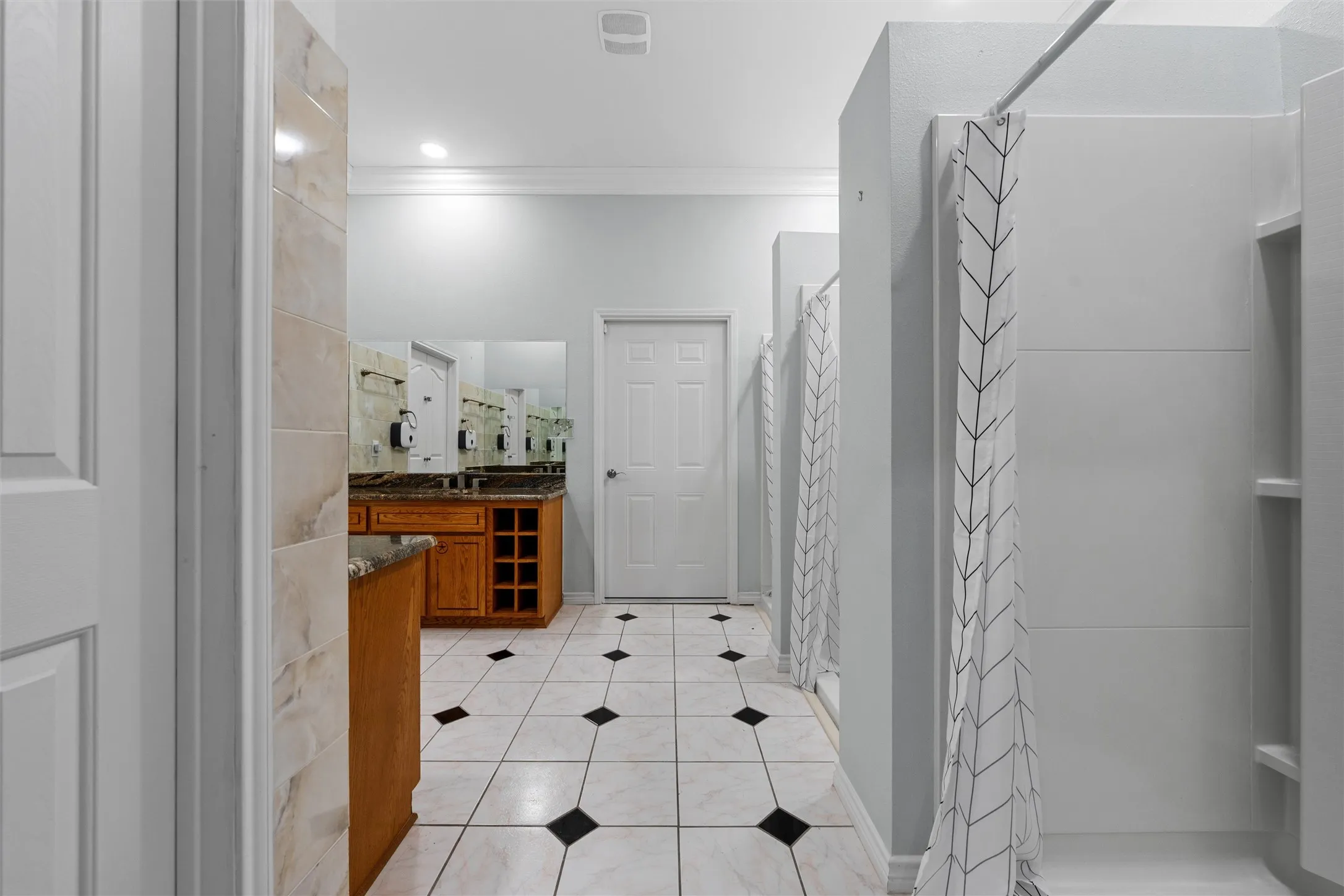 Bathroom with a stall shower, vanity, light tile patterned floors, and ornamental molding