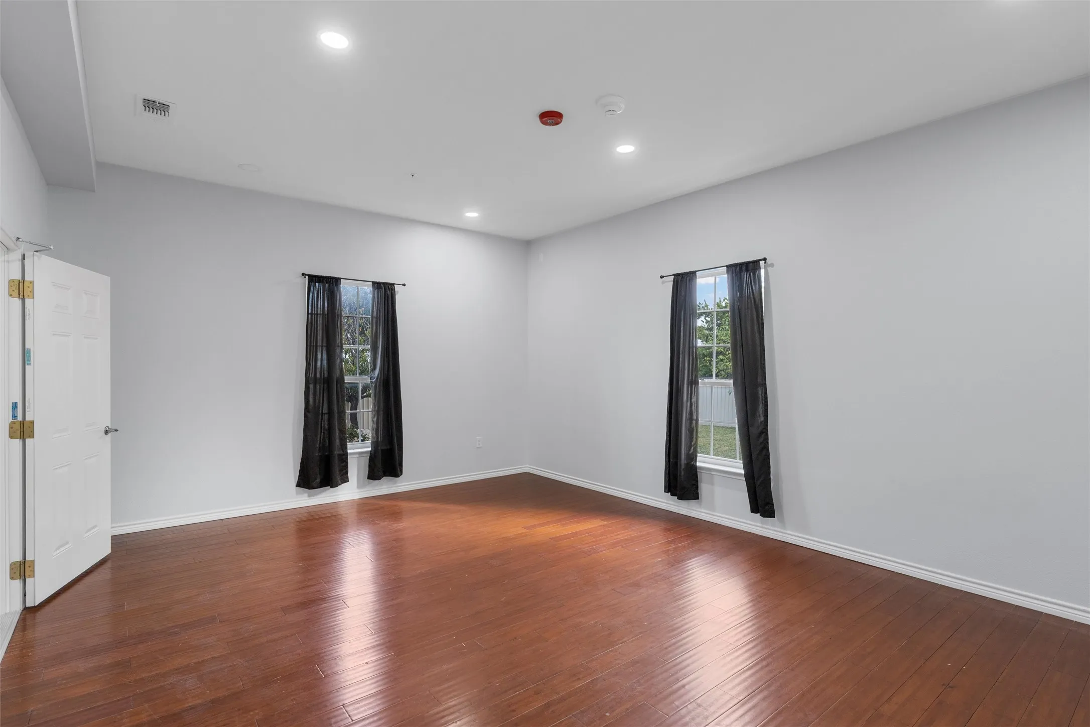 Empty room featuring recessed lighting, hardwood / wood-style floors, and healthy amount of natural light