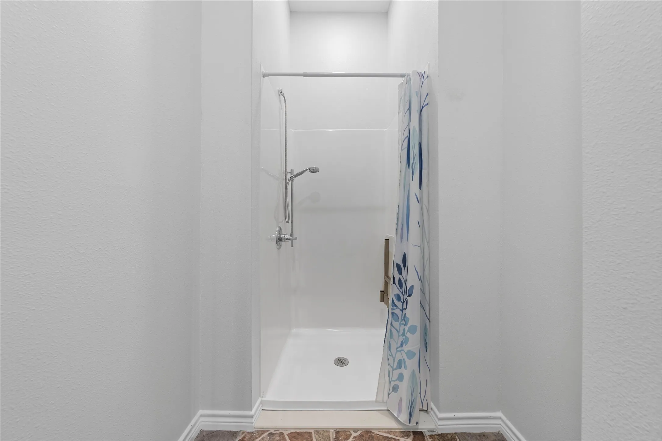 Bathroom with a shower stall and a textured wall