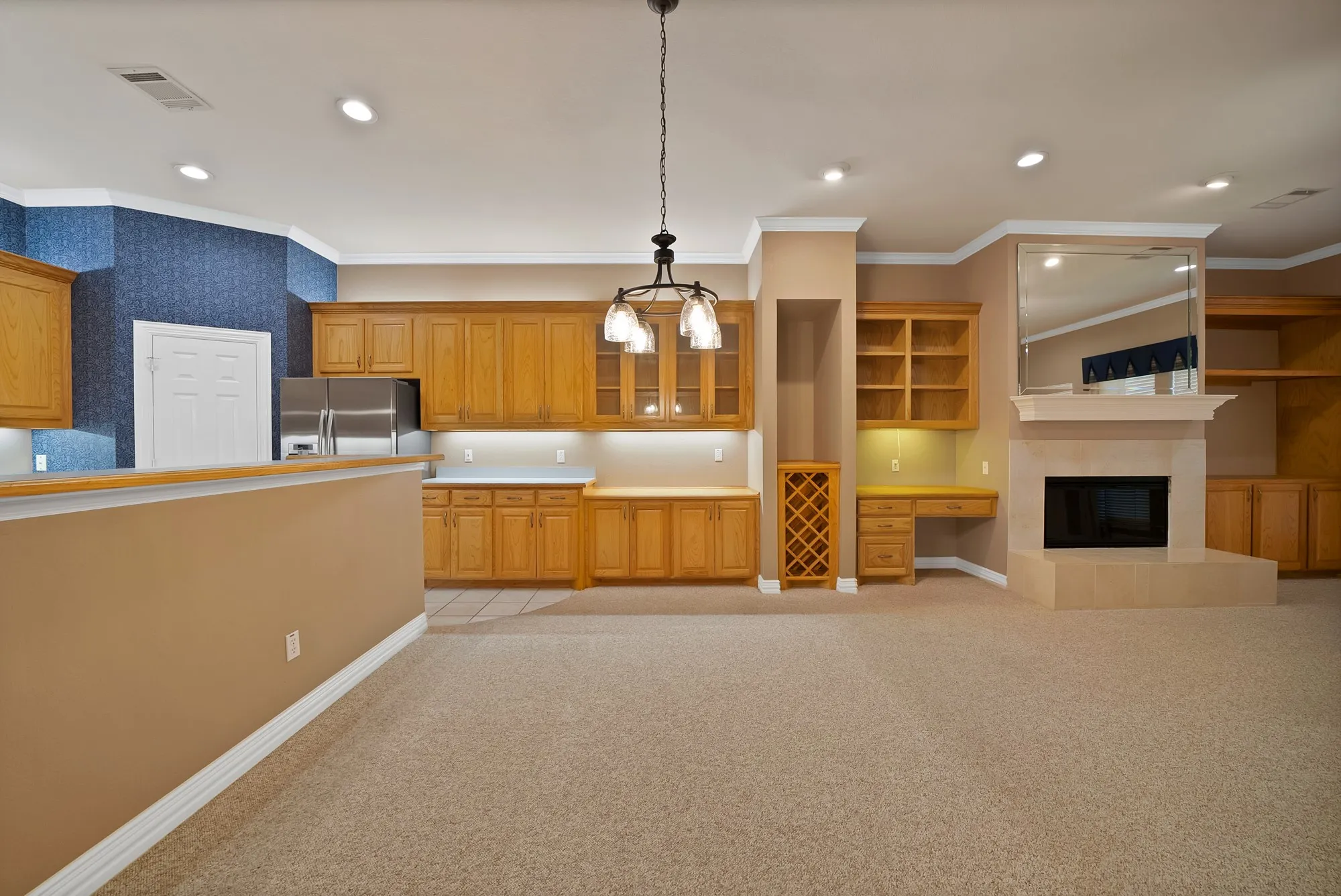 Kitchen featuring light carpet, ornamental molding, light countertops, a tiled fireplace, and pendant lighting