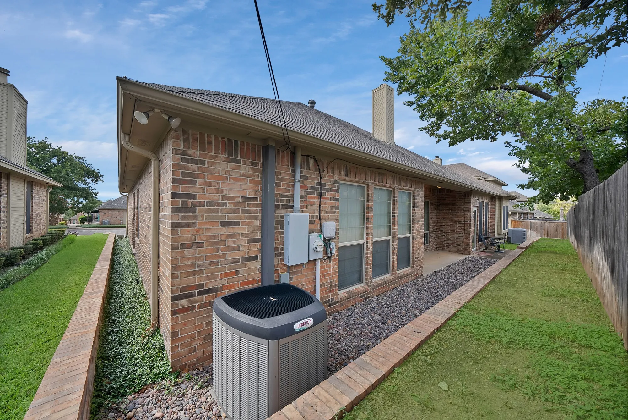 View of property exterior with brick siding, a patio area, a chimney, and a fenced backyard
