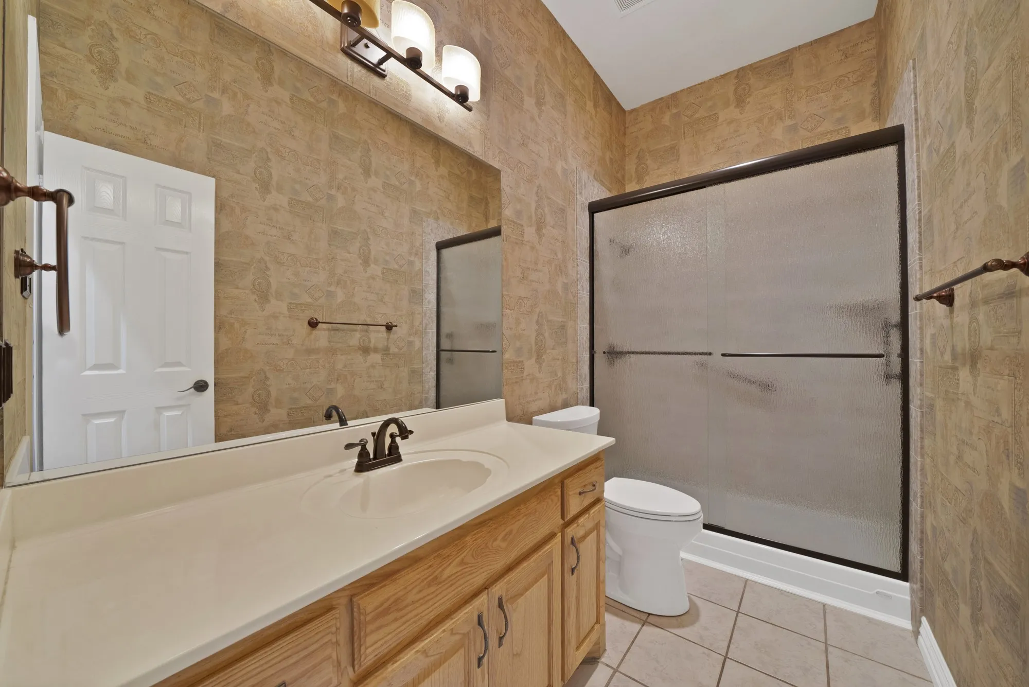 Bathroom featuring light tile patterned floors, a shower stall, and vanity