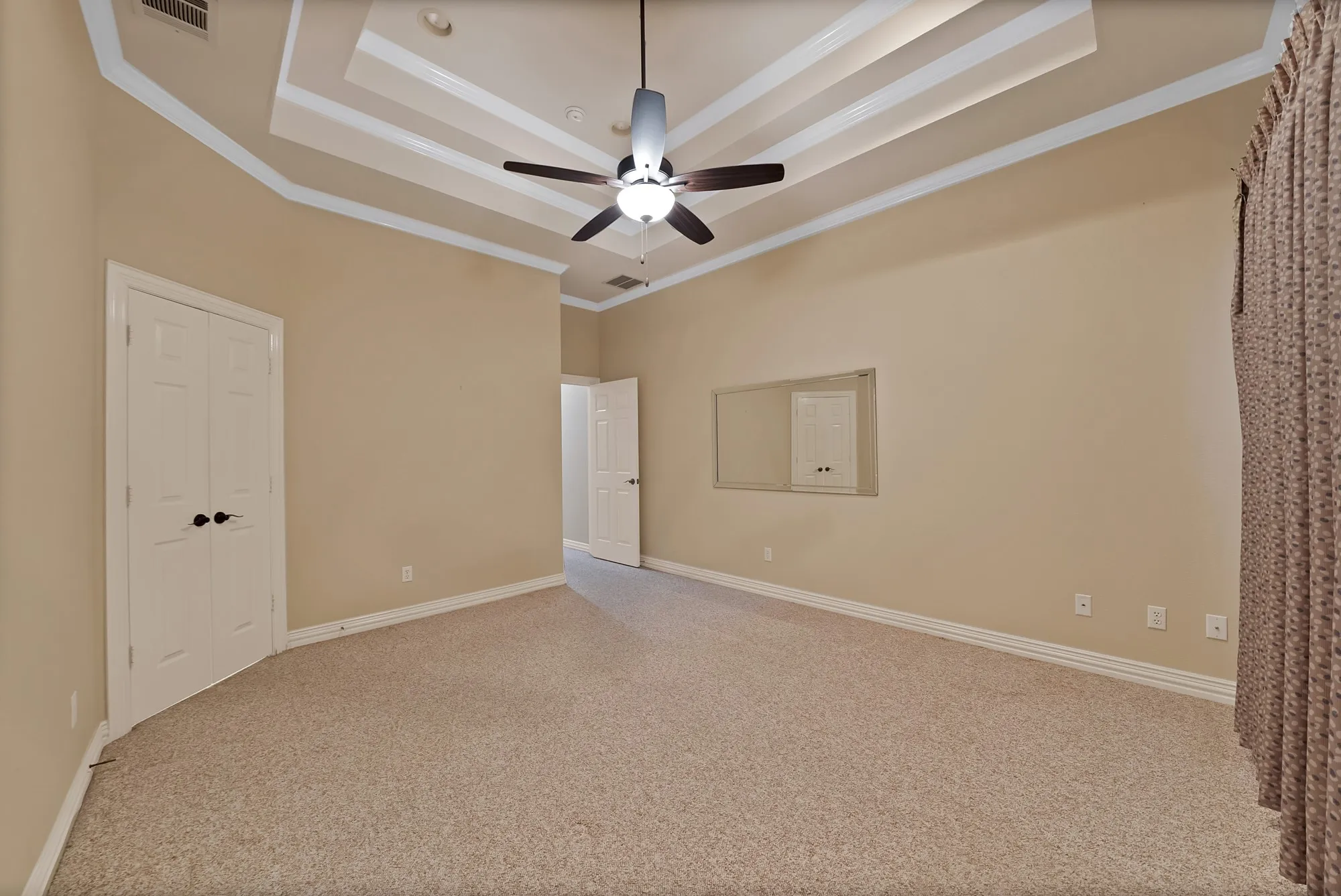 Unfurnished bedroom with a raised ceiling, carpet flooring, crown molding, and a ceiling fan