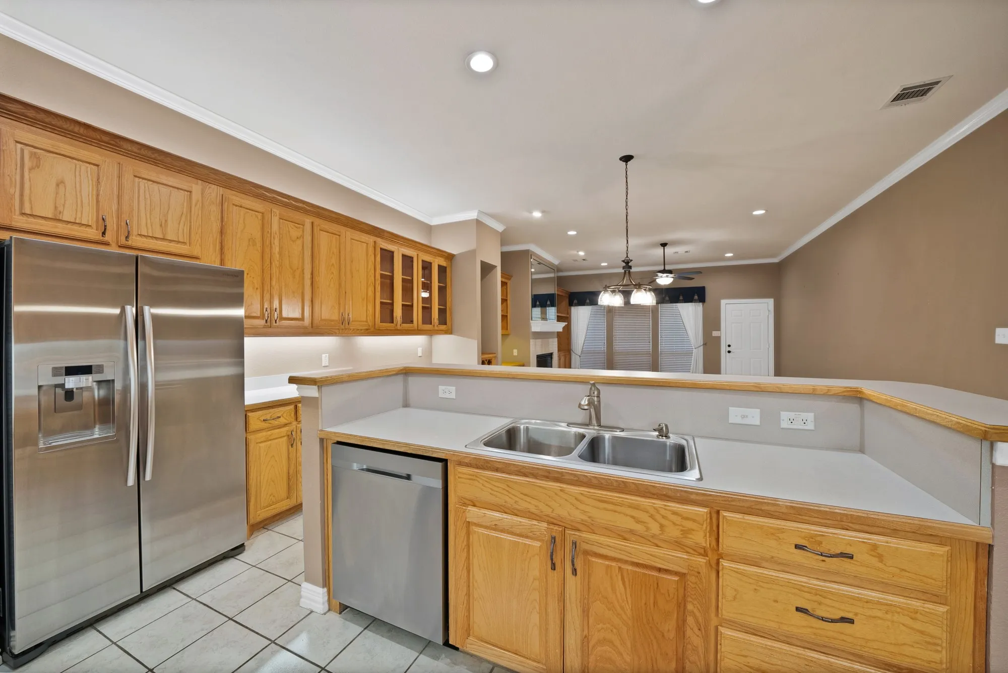 Kitchen featuring stainless steel appliances, light countertops, glass insert cabinets, light tile patterned floors, and ornamental molding