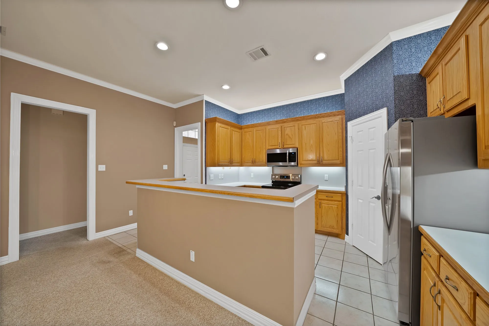 Kitchen featuring crown molding, appliances with stainless steel finishes, light countertops, recessed lighting, and light tile patterned flooring