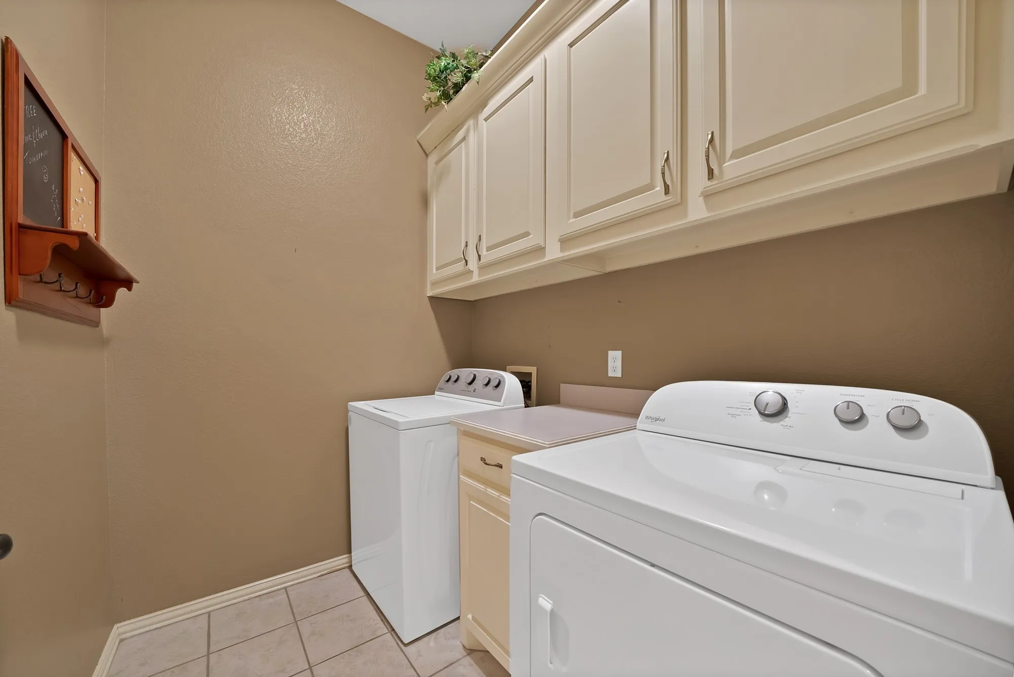 Washroom with light tile patterned floors, washing machine and dryer, and cabinet space