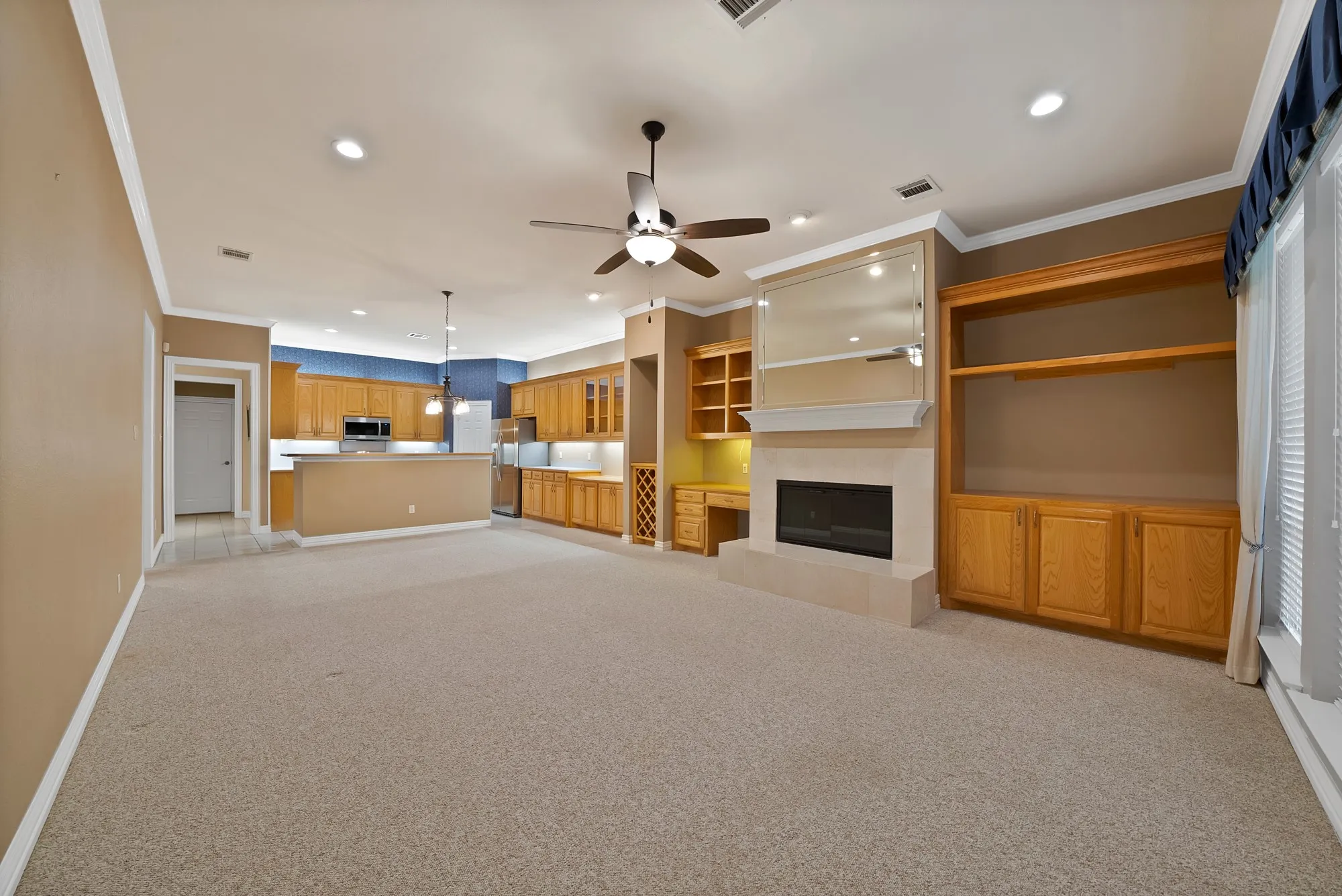 Unfurnished living room with crown molding, light carpet, a fireplace, recessed lighting, and a ceiling fan