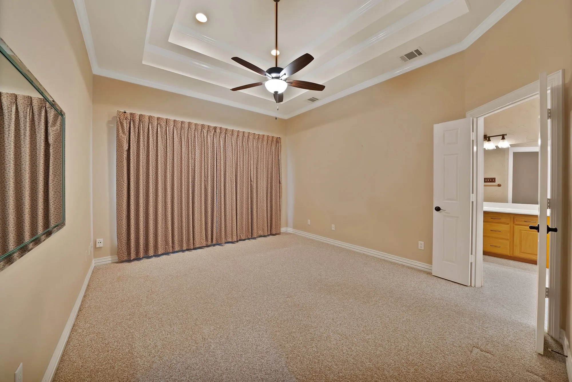 Empty room featuring light carpet, a tray ceiling, crown molding, and ceiling fan