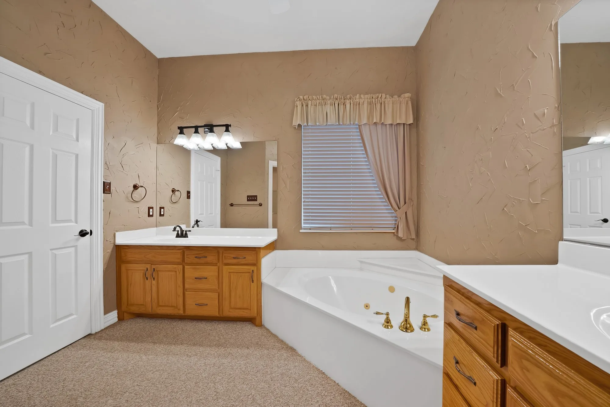 Full bath with a textured wall, two vanities, and a jetted tub