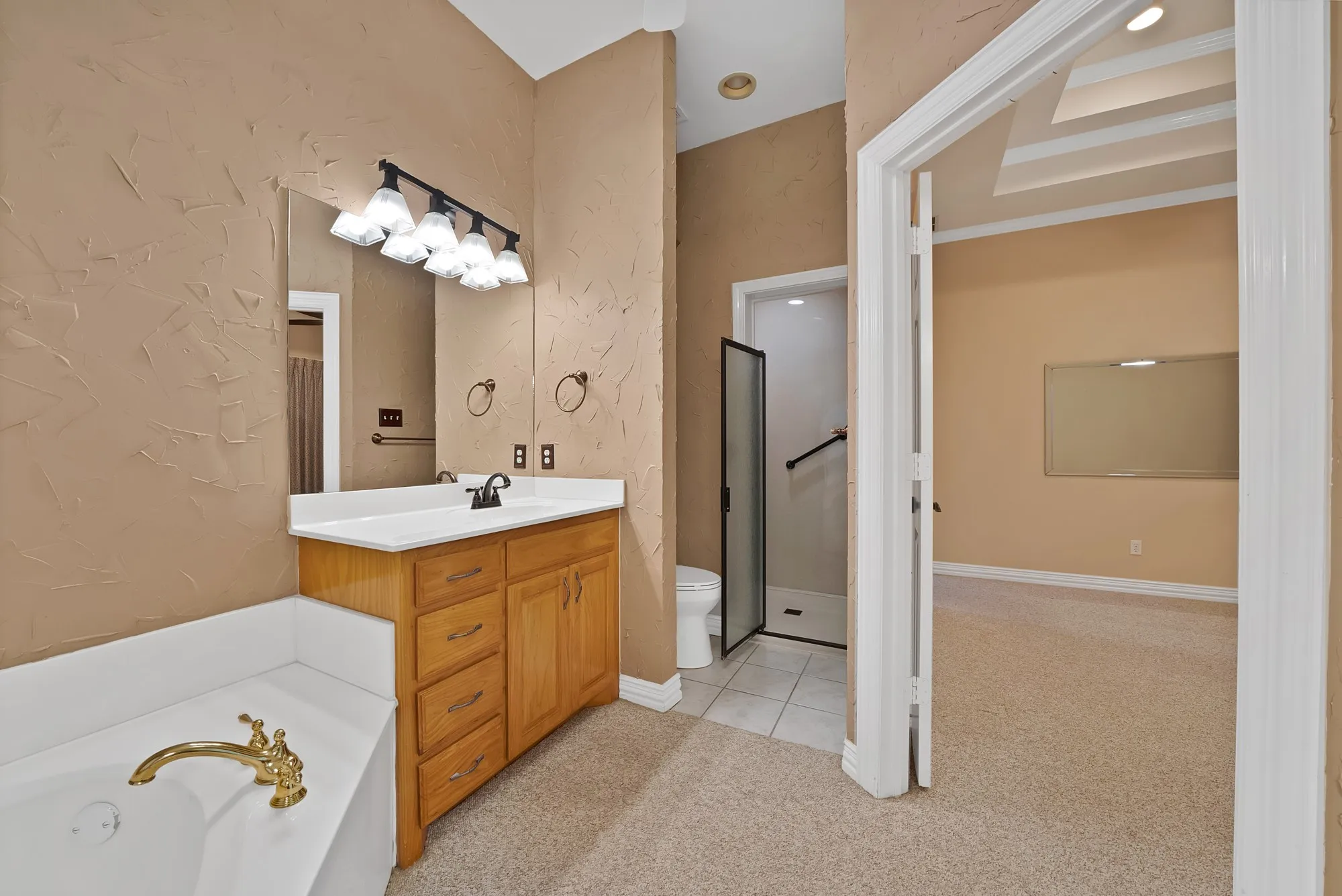 Full bathroom featuring vanity, a bath, a textured wall, light tile patterned flooring, and a shower stall