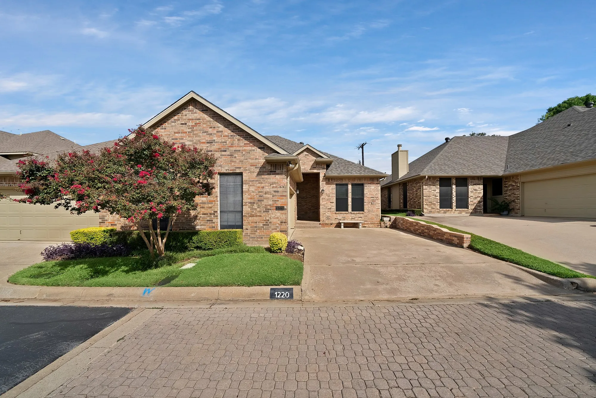 Ranch-style house with concrete driveway, brick siding, and a shingled roof
