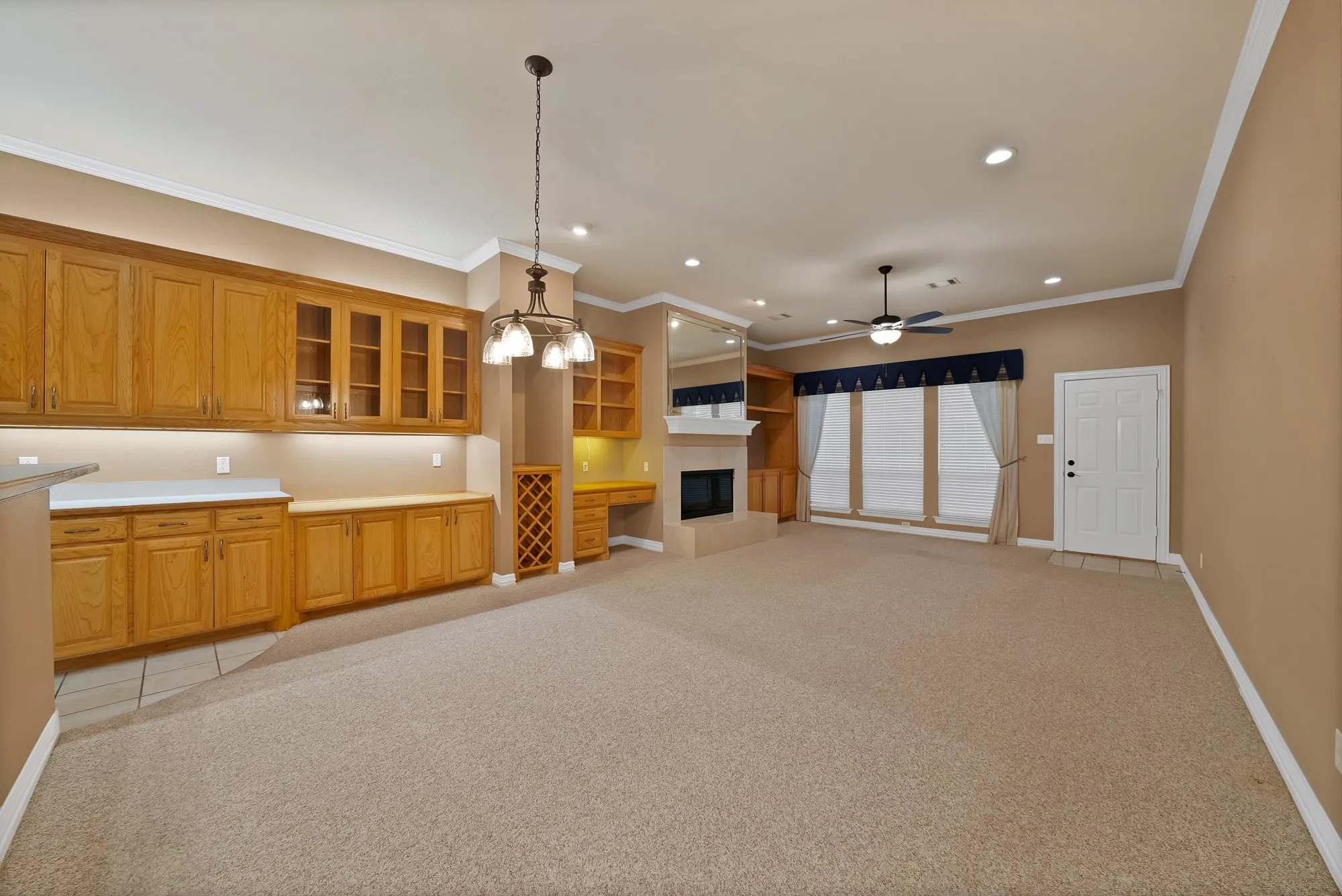 Kitchen featuring light colored carpet, light countertops, pendant lighting, brown cabinets, and a fireplace