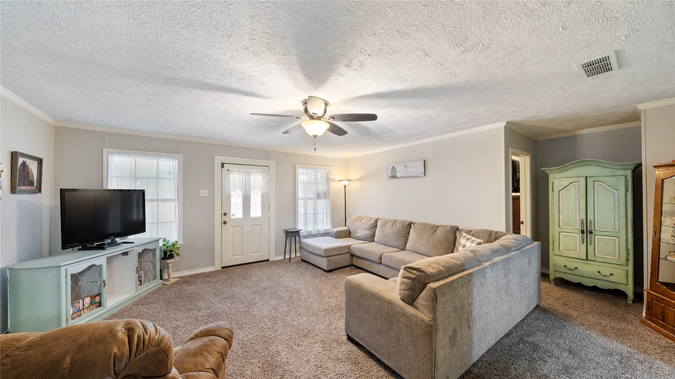 Living room with carpet floors, a textured ceiling, crown molding, and a ceiling fan