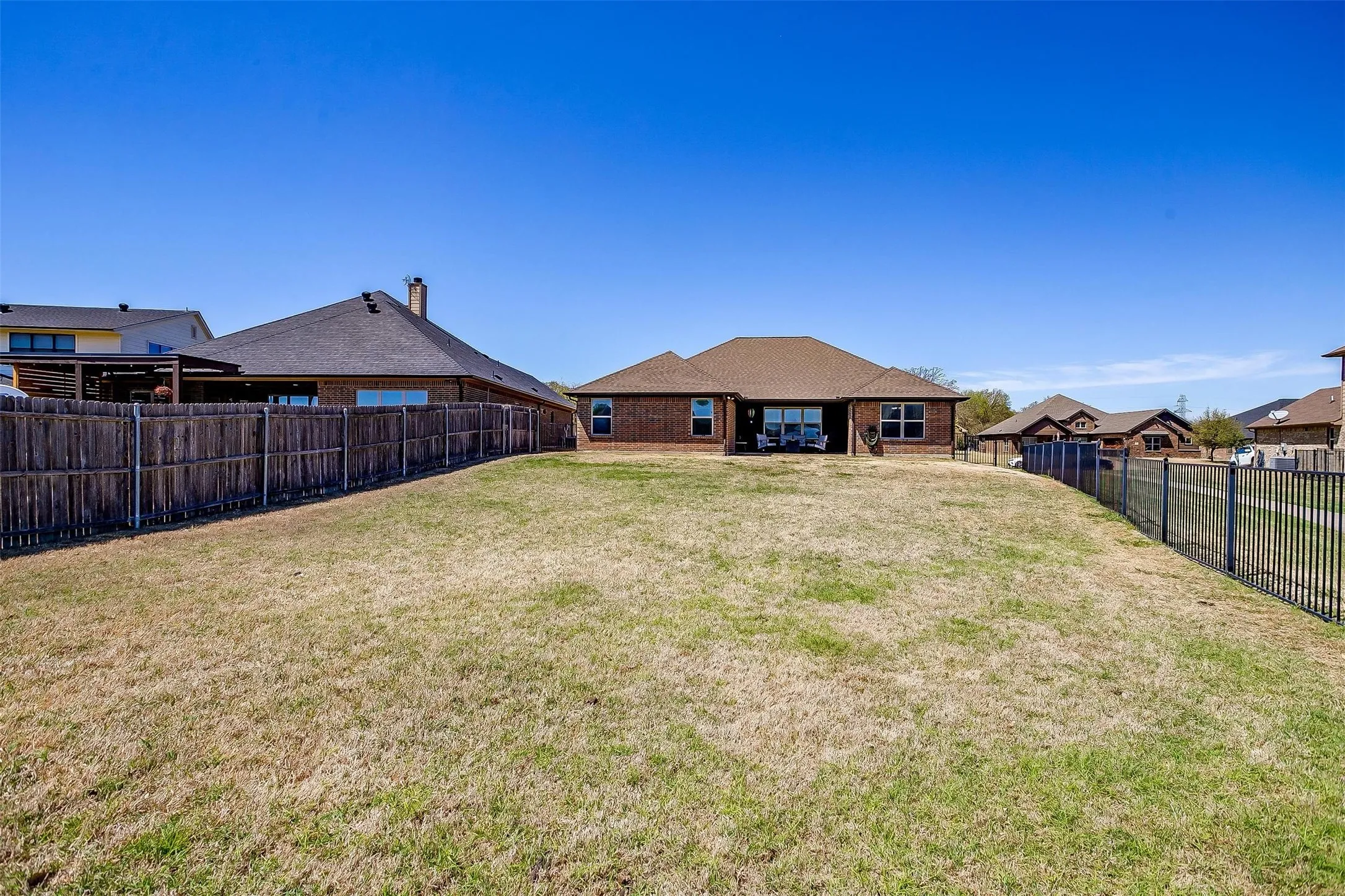 Back of house with a fenced backyard and brick siding