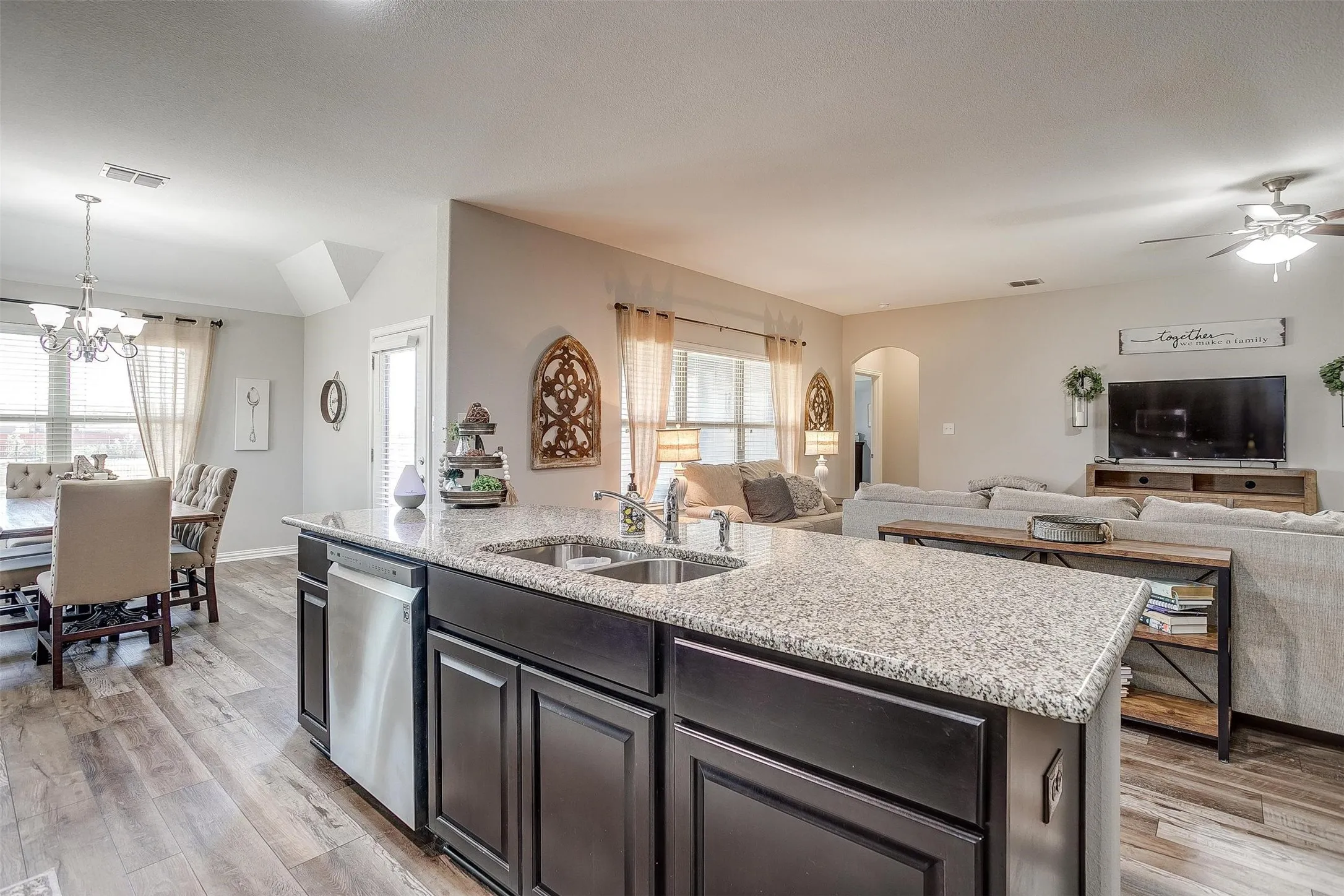 Kitchen featuring light wood-style floors, light stone countertops, a kitchen island with sink, and open floor plan