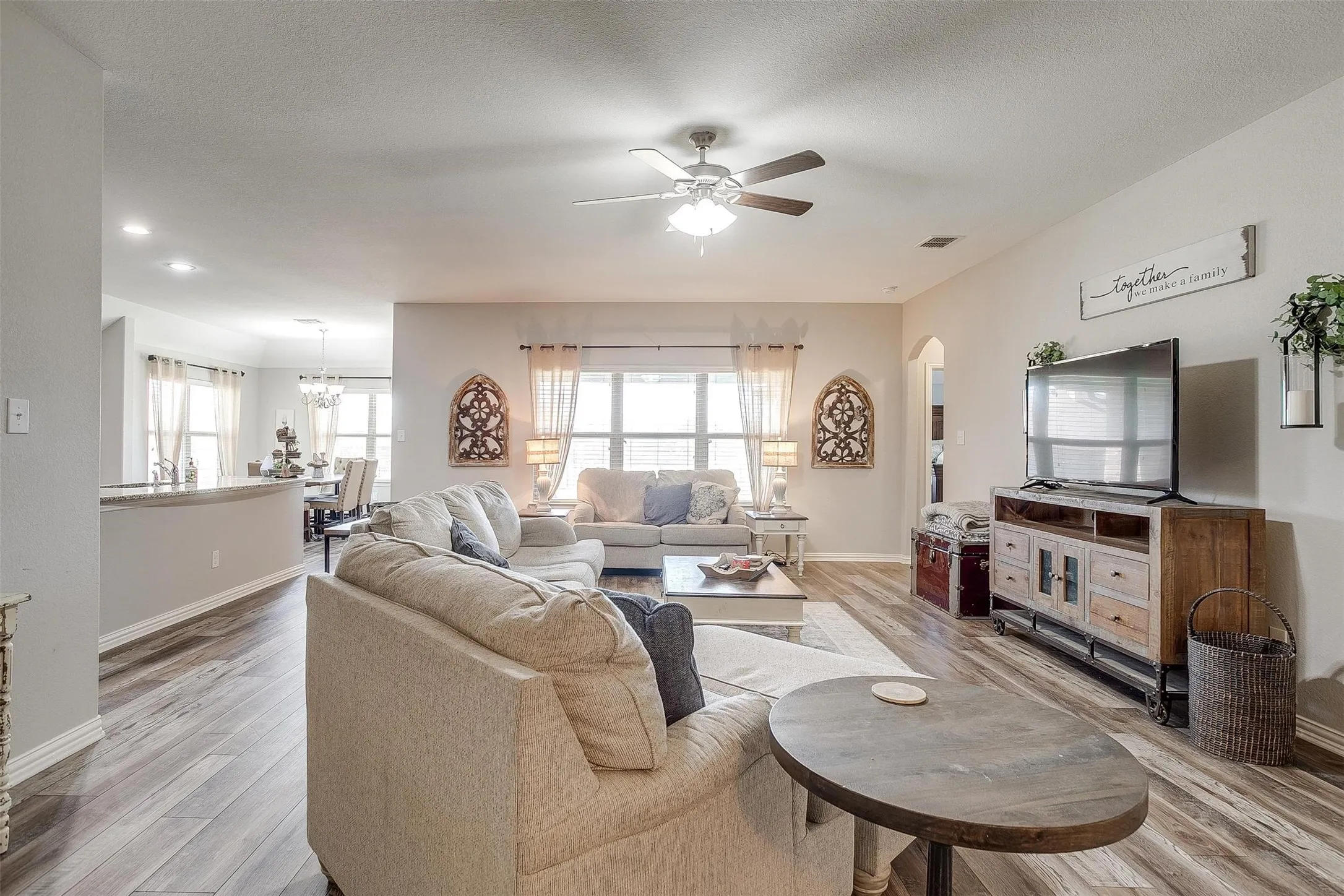 Living area featuring light wood-style floors, ceiling fan, and arched walkways