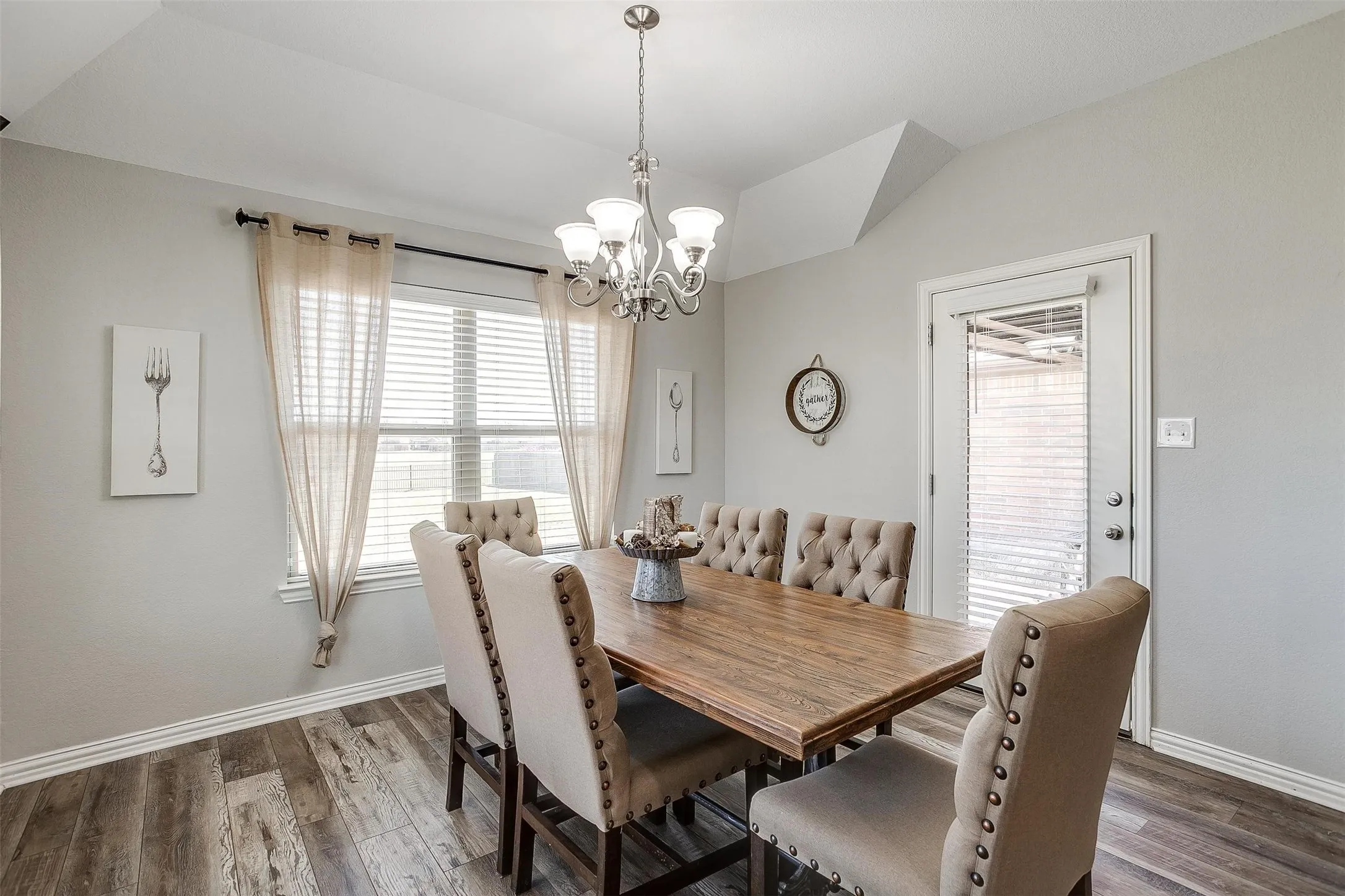 Dining area with dark wood-type flooring, a chandelier, and lofted ceiling