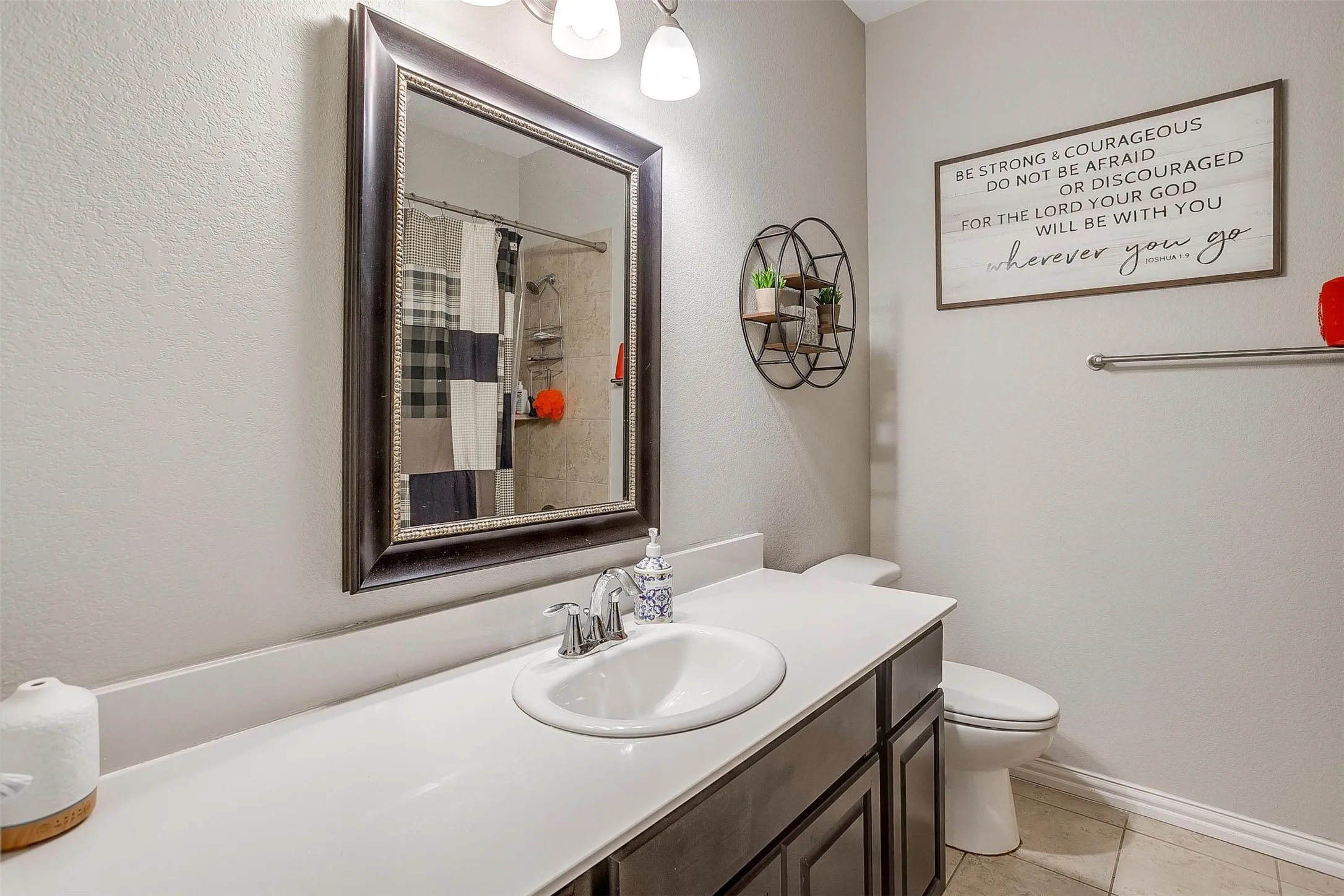 Bathroom featuring vanity, light tile patterned floors, a textured wall, and curtained shower