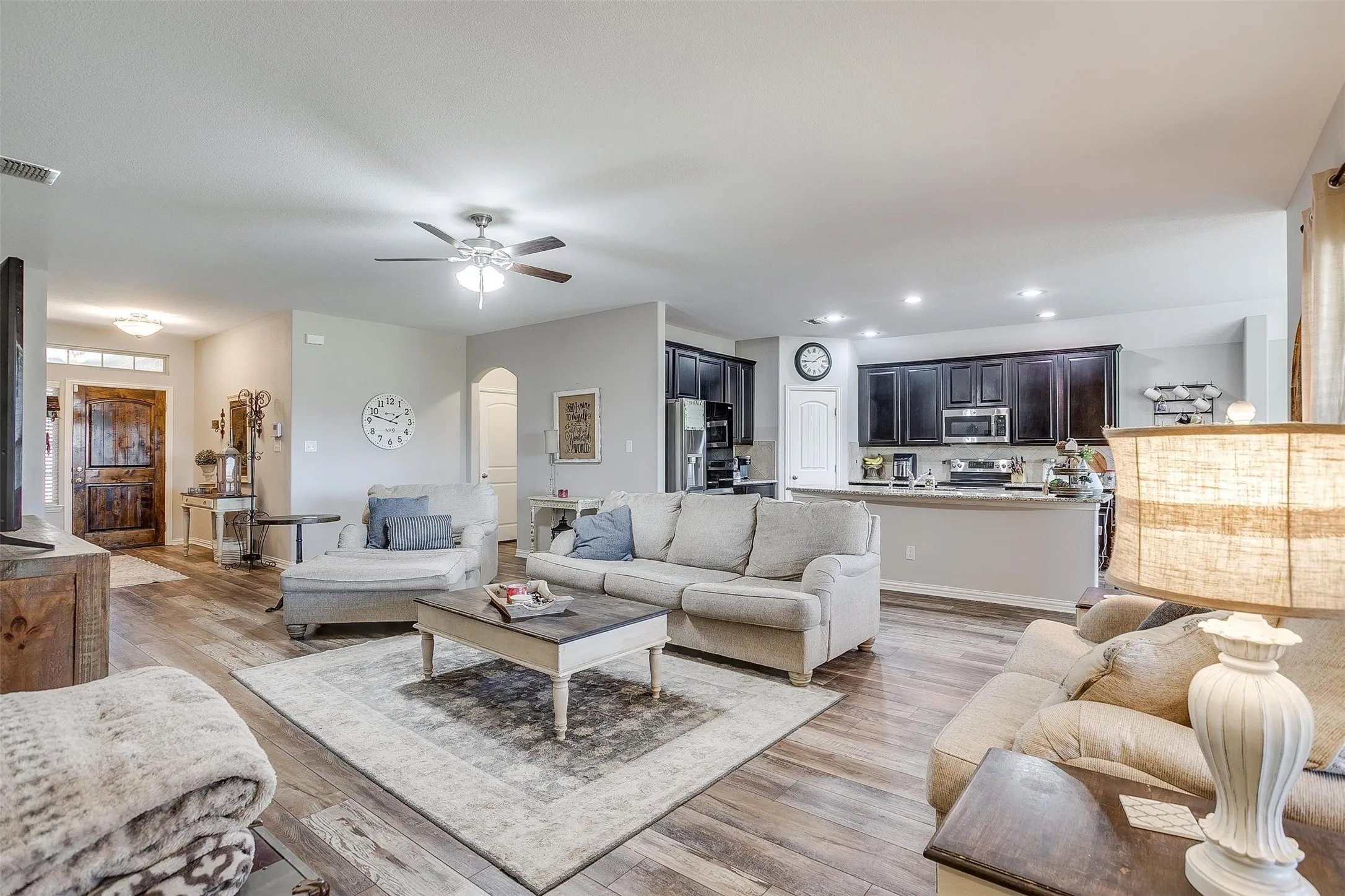 Living room featuring light wood-style flooring, arched walkways, ceiling fan, and recessed lighting