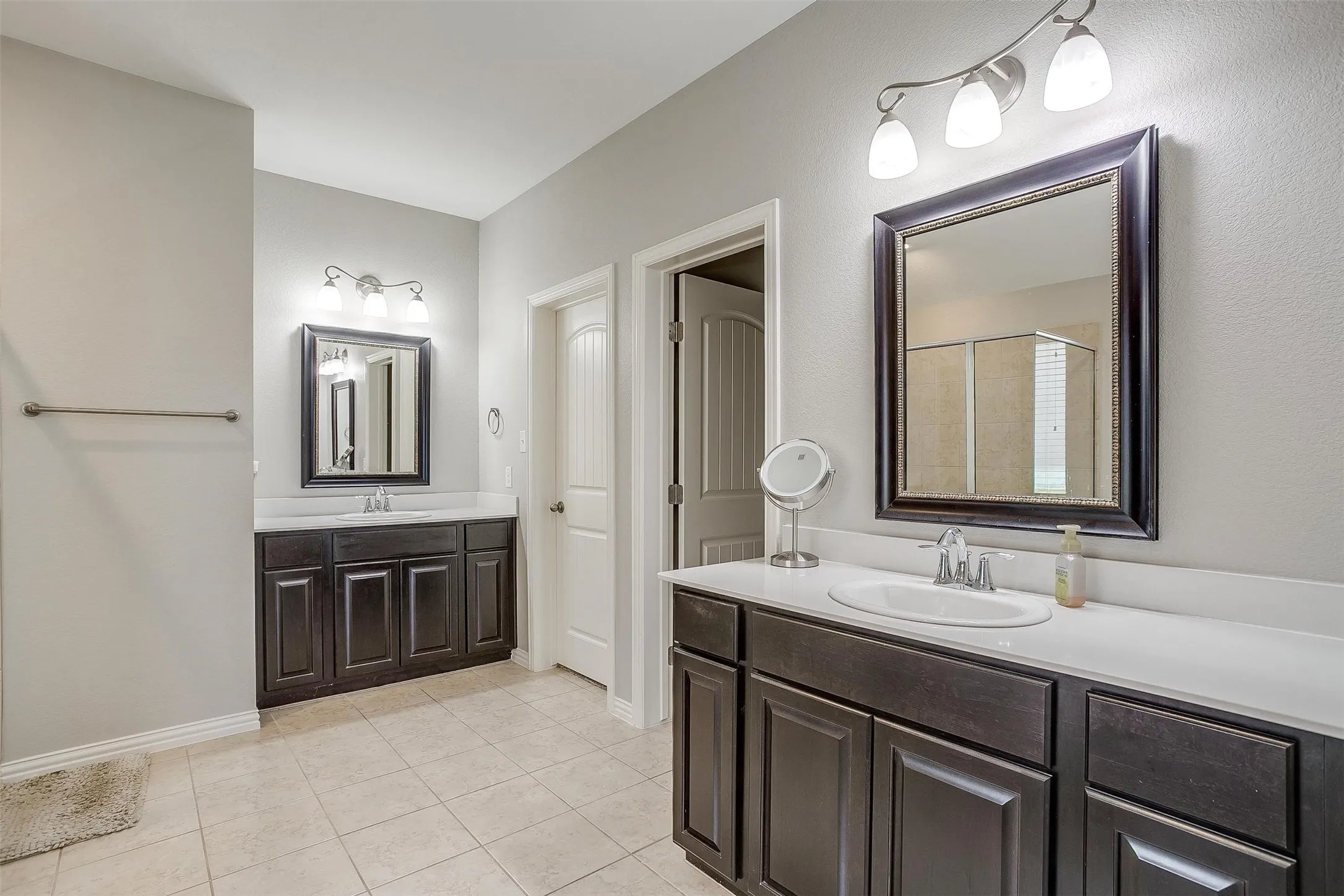 Bathroom with a shower stall, two vanities, and light tile patterned floors